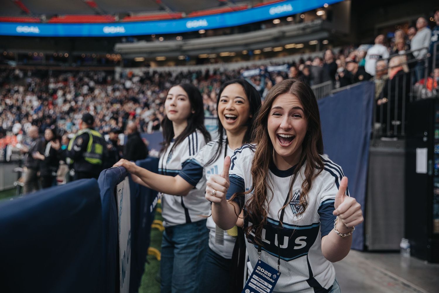 Excited fans cheer and celebrate in the stadium stands during a sporting event.