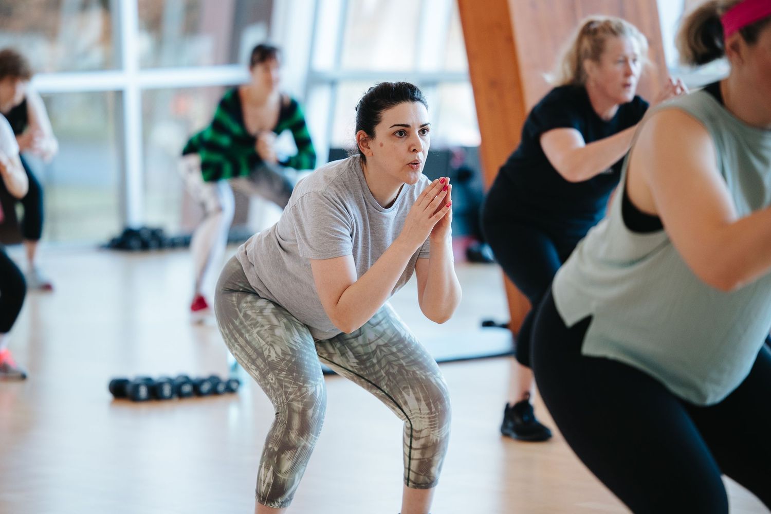 Group fitness class participants doing aerobic exercises in a studio.