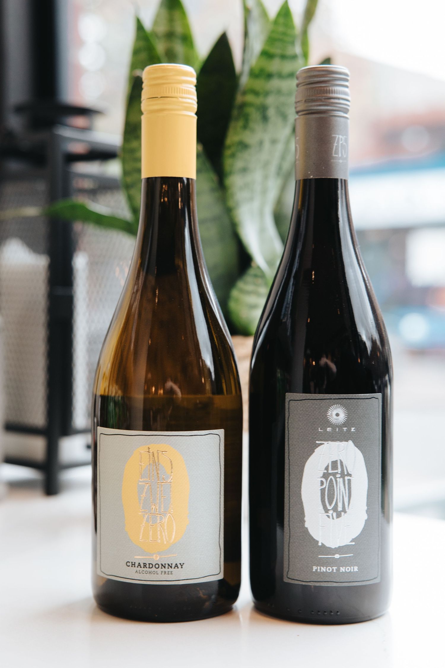 Elegant wine bottles with minimalist grey and gold labels displayed on a white surface.