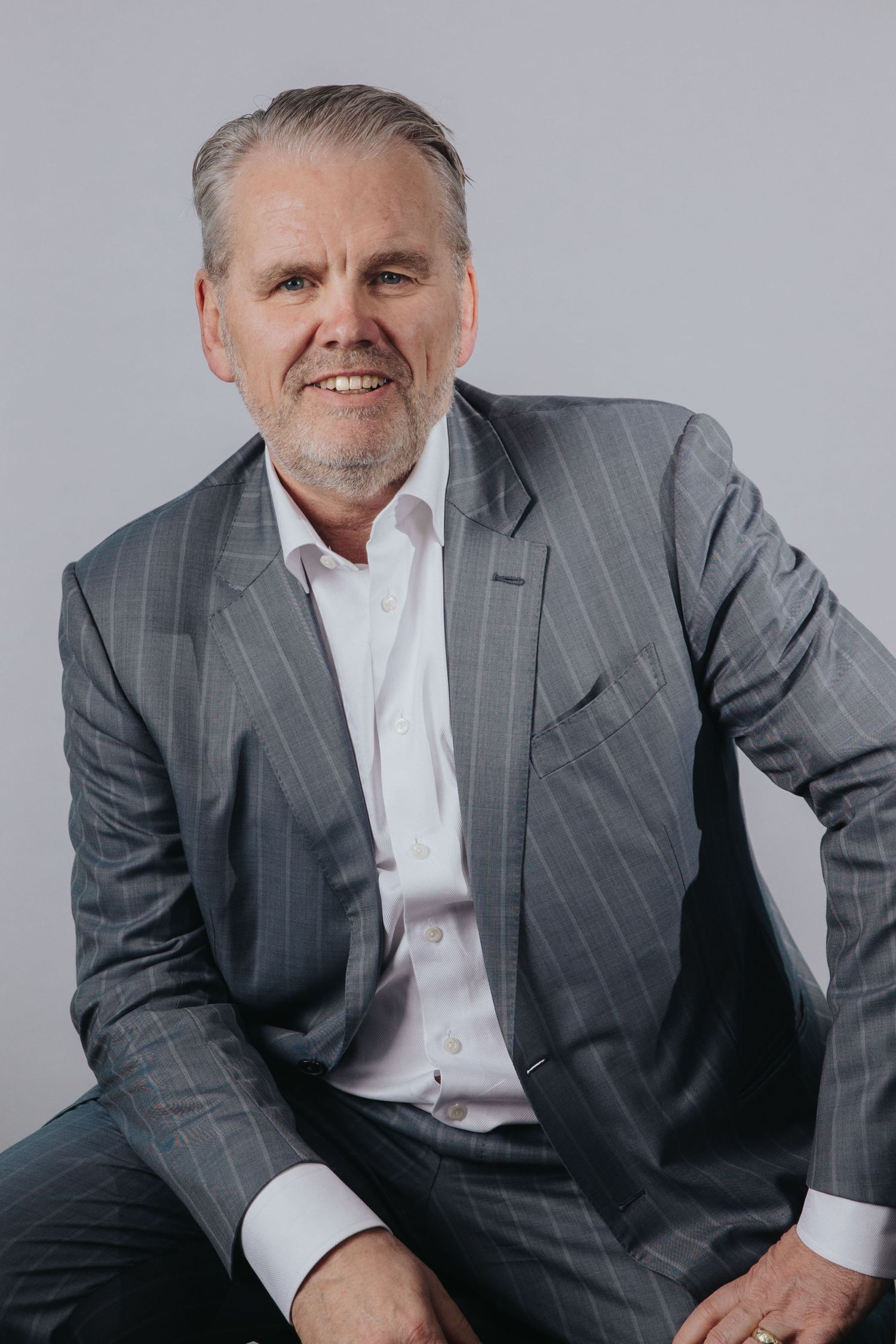 Person in pinstriped suit and white shirt photographed in studio setting.