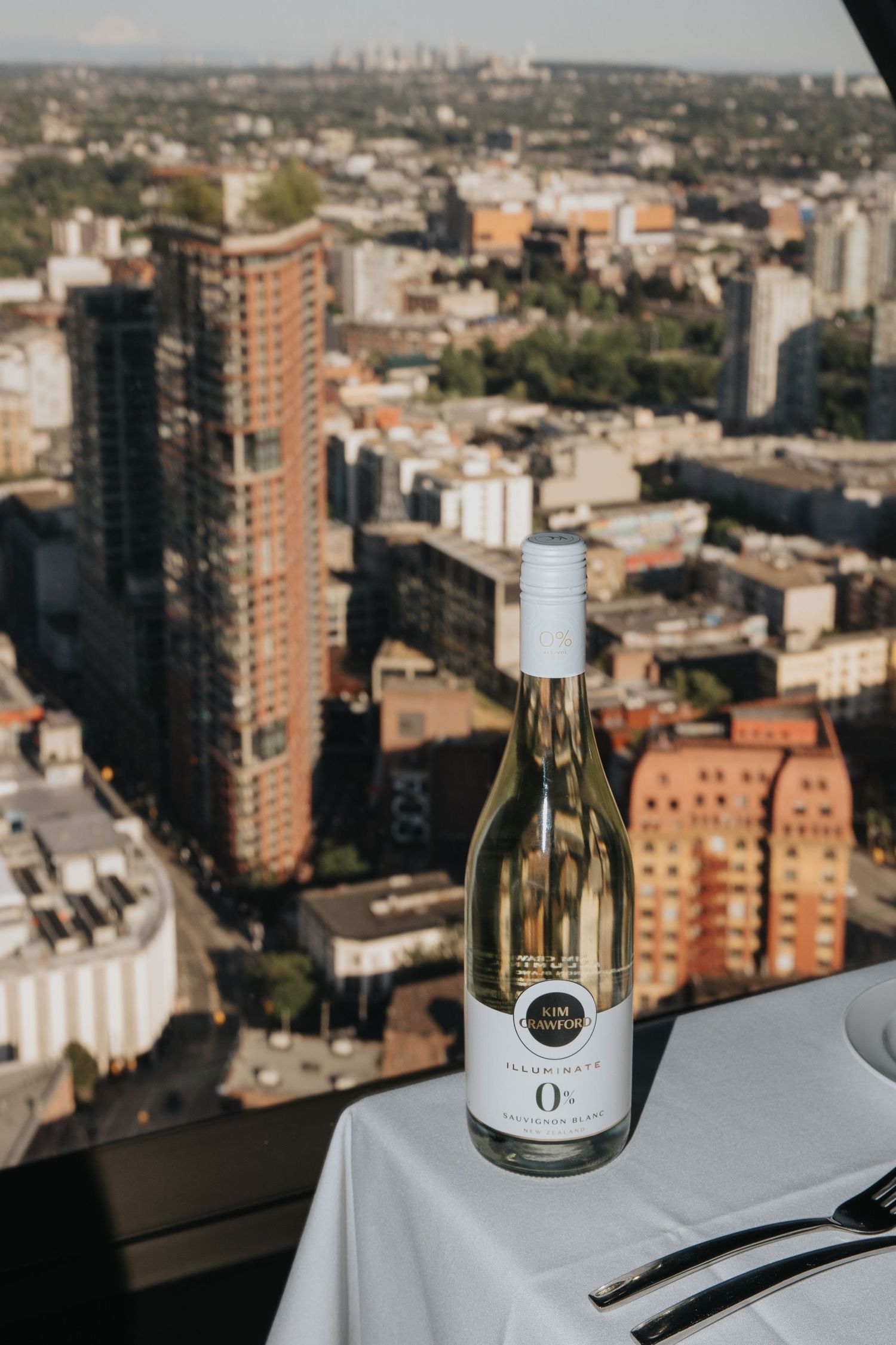 Wine bottles on white tablecloth with city skyline view in background.