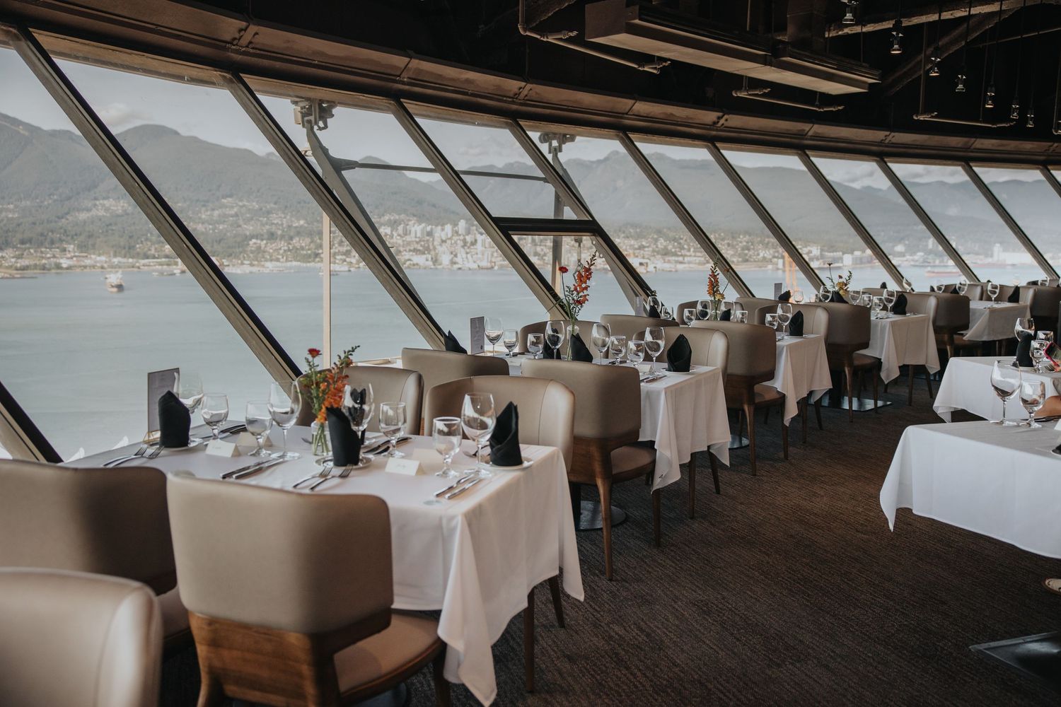 Elegant banquet hall setup with white tablecloths and large windows.