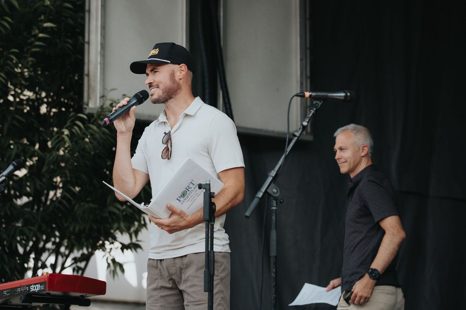 Performers on stage during outdoor community event with sound equipment setup.