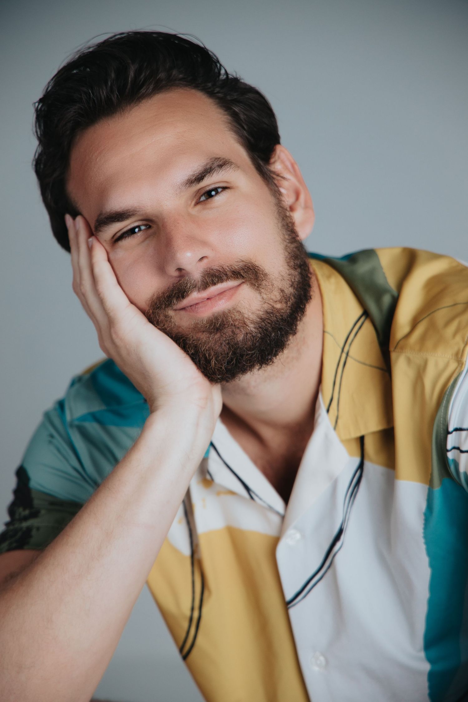 Professional portrait series showing playful expressions while wearing a yellow jacket against a teal background.