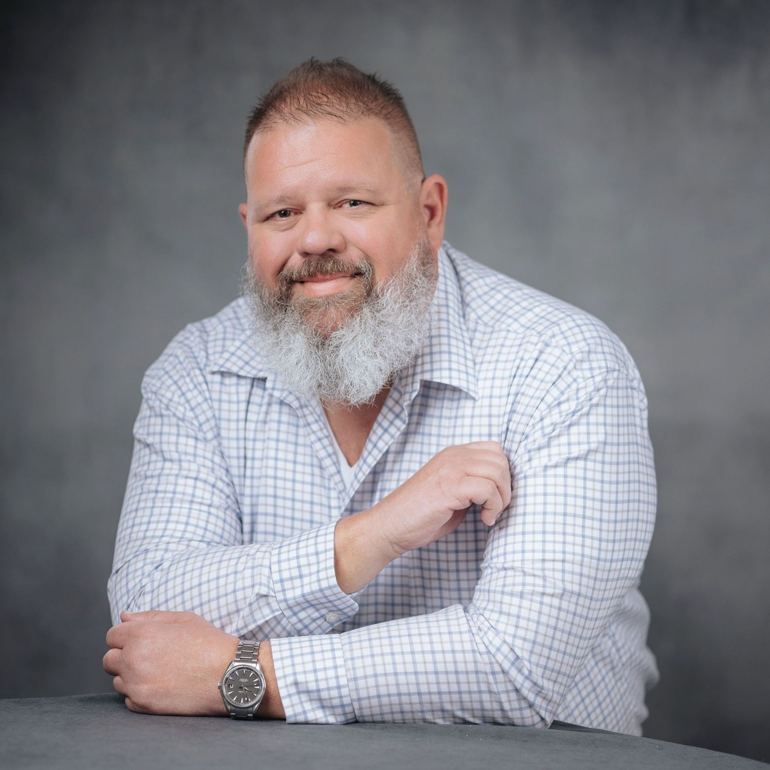 Professional headshot photo series showing different poses and expressions in a white checkered shirt.