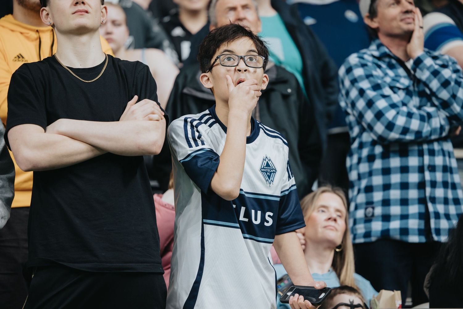 Stadium crowd reacts emotionally while watching an intense sports moment.