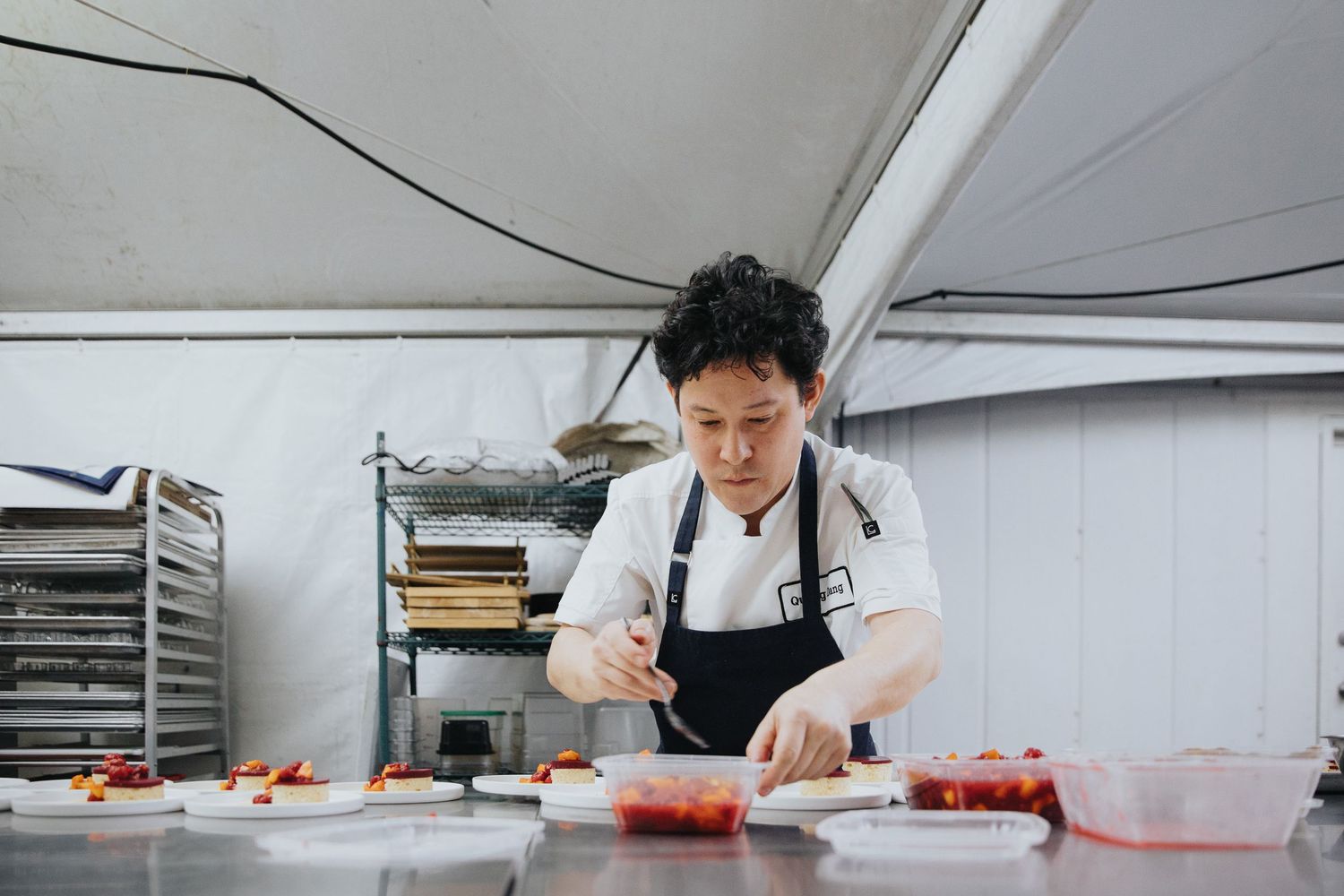 Professional kitchen workspace with chef preparing ingredients on stainless steel counter.