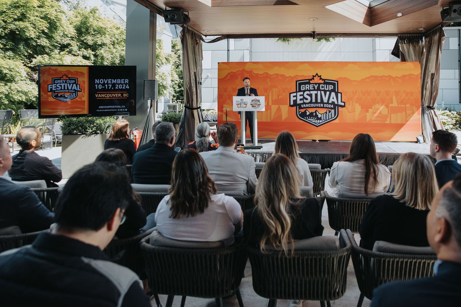 Conference attendees seated in rows watching a presentation with an orange festival banner backdrop.