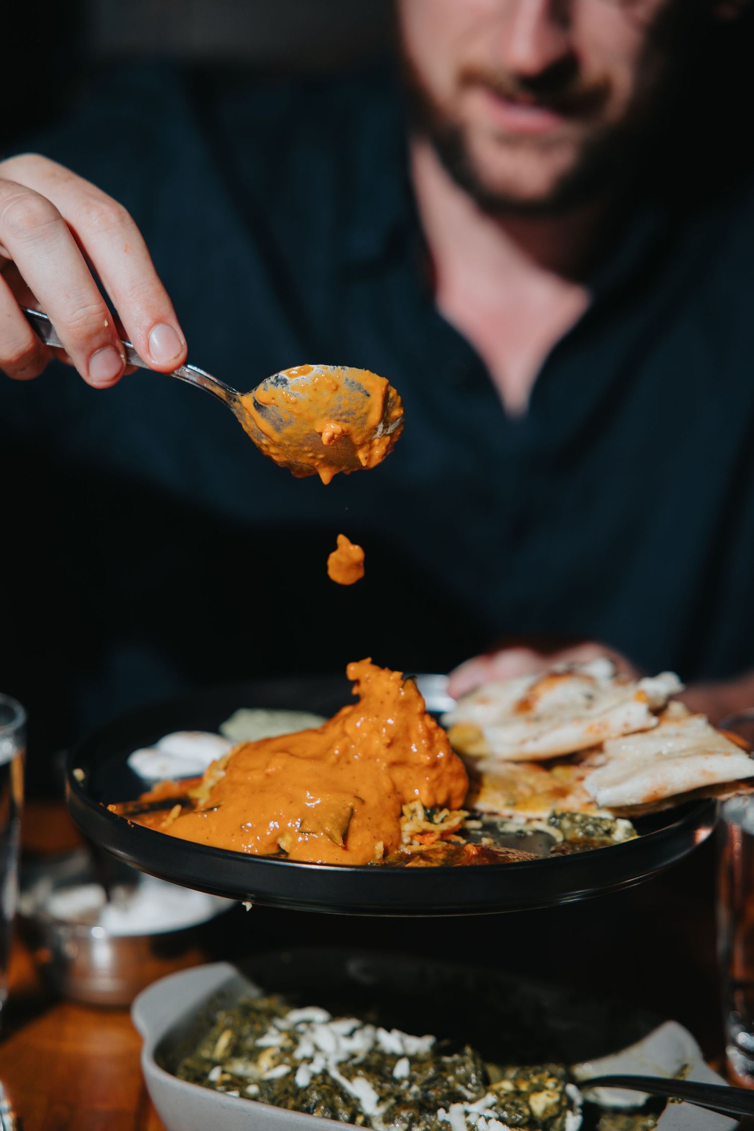 Orange curry dish being served at a restaurant table.