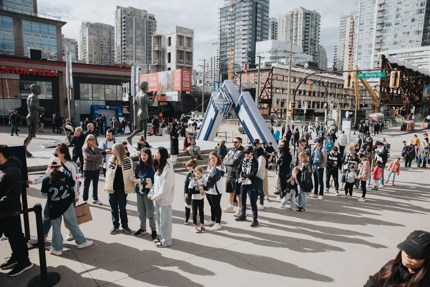 Crowd of soccer fans gathering at an urban intersection with high-rise buildings in the background.