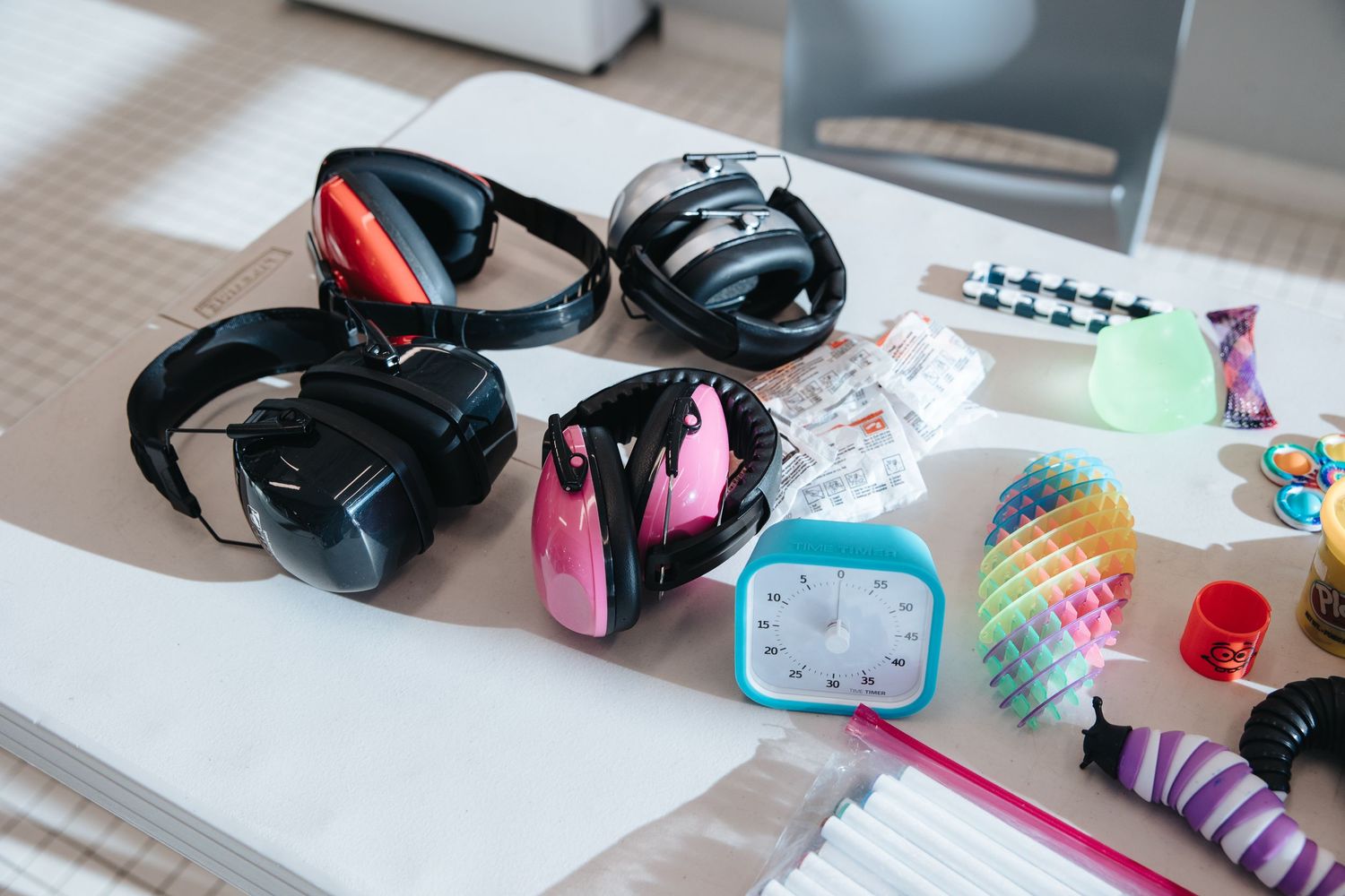 Collection of headphones, colorful stationery items and school supplies arranged on a desk.