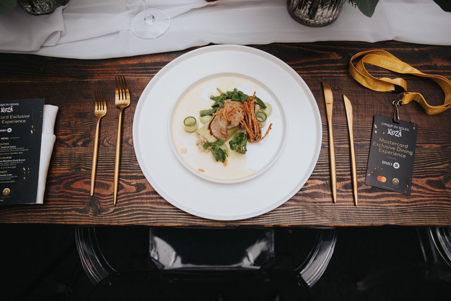 Overhead view of elegant place settings on wooden table with gold cutlery and menu cards.