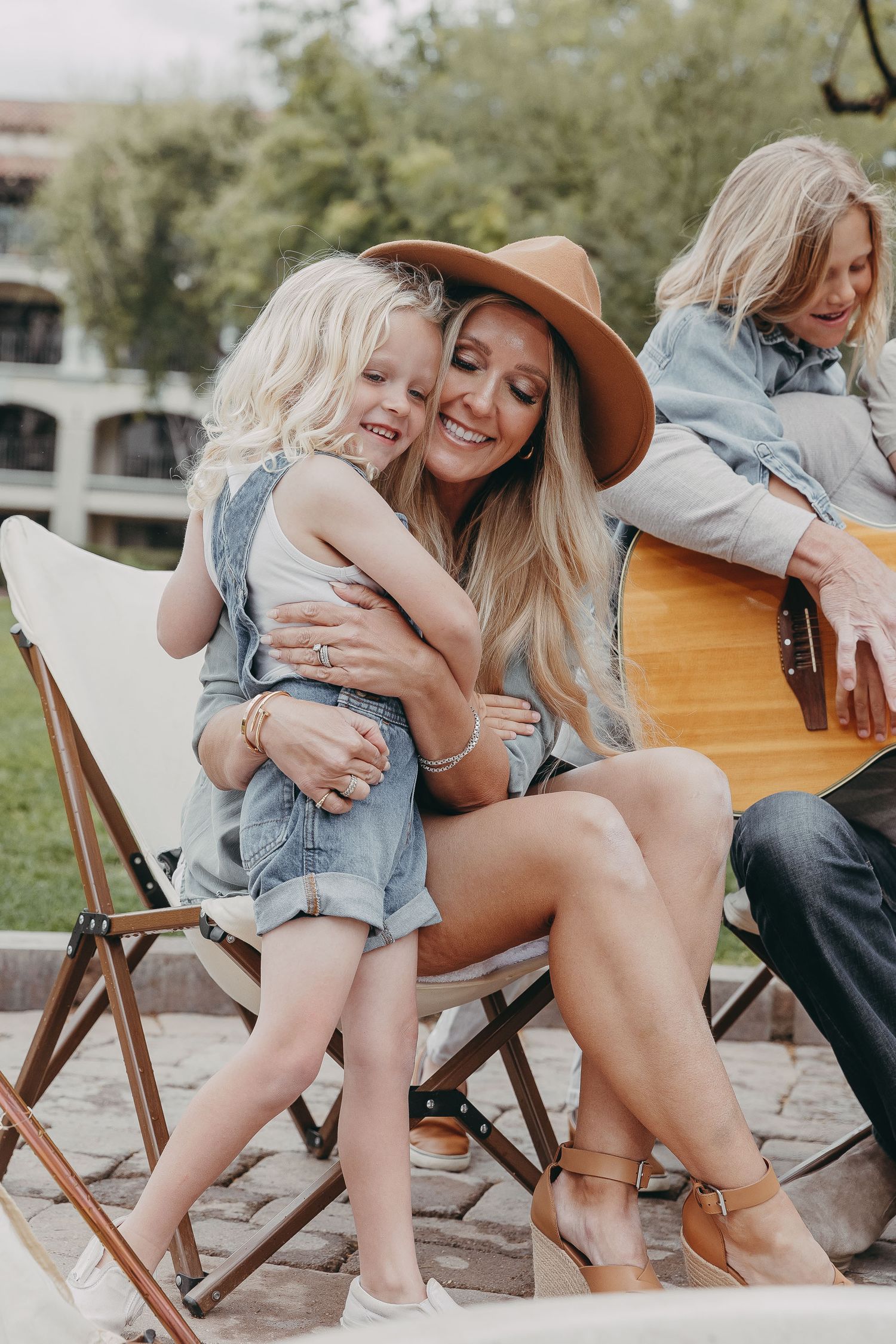 Candid moments of laughter and joy captured on wooden folding chairs in a park setting.