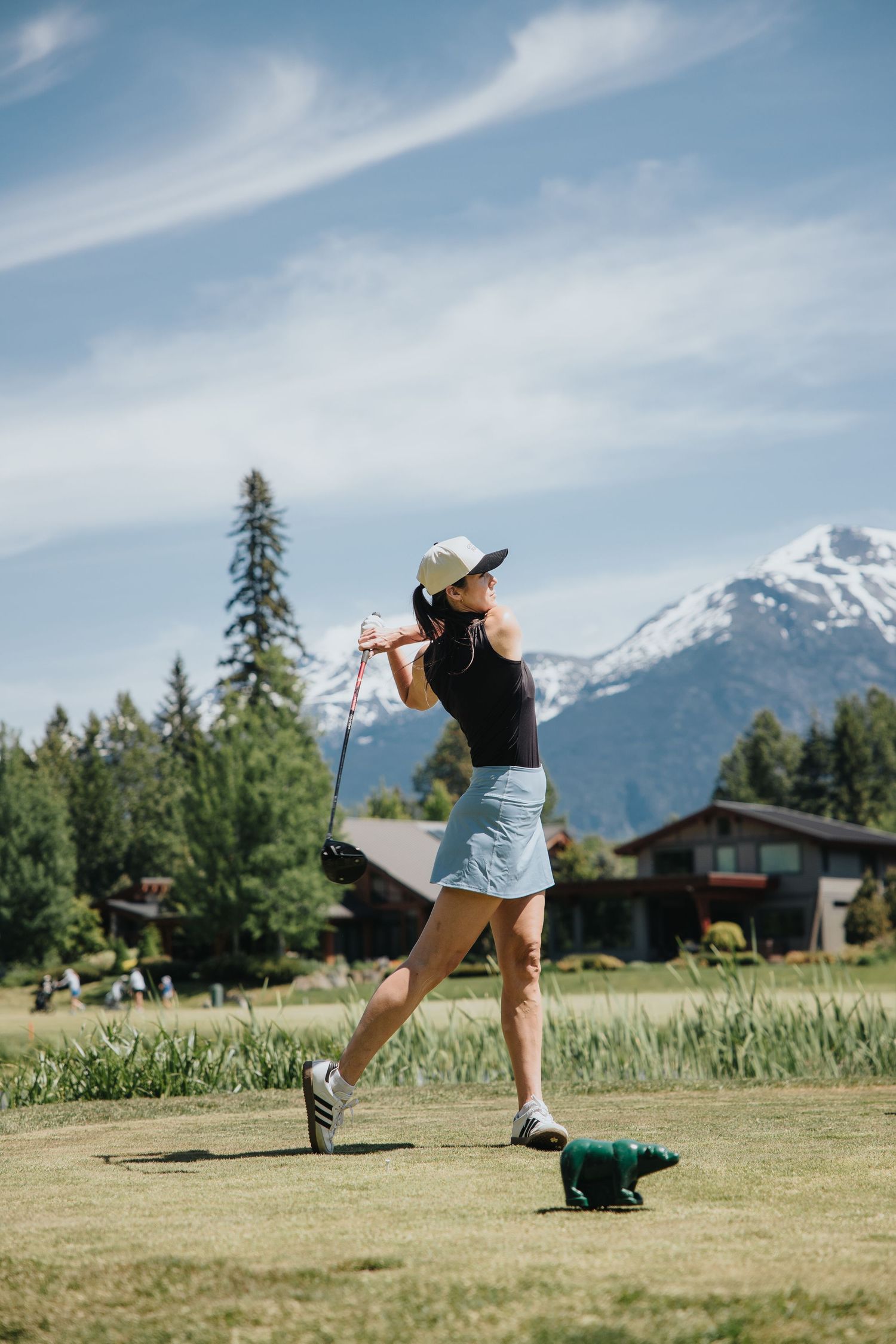 Person playing golf on a scenic course with mountain views in the background.