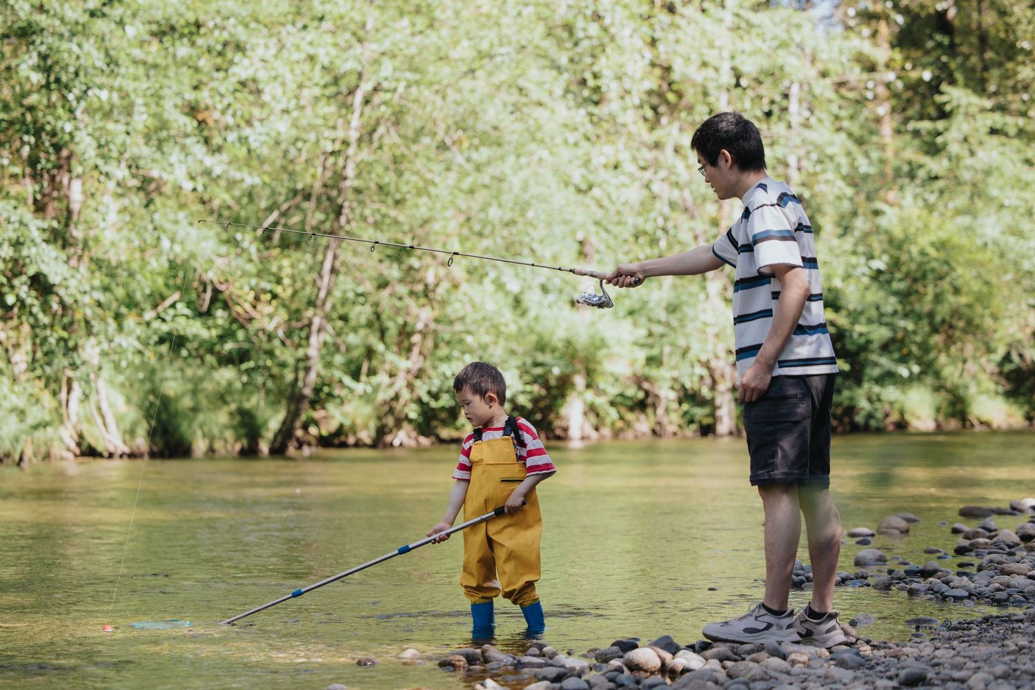 Kids exploring and wading in stream with fishing nets.