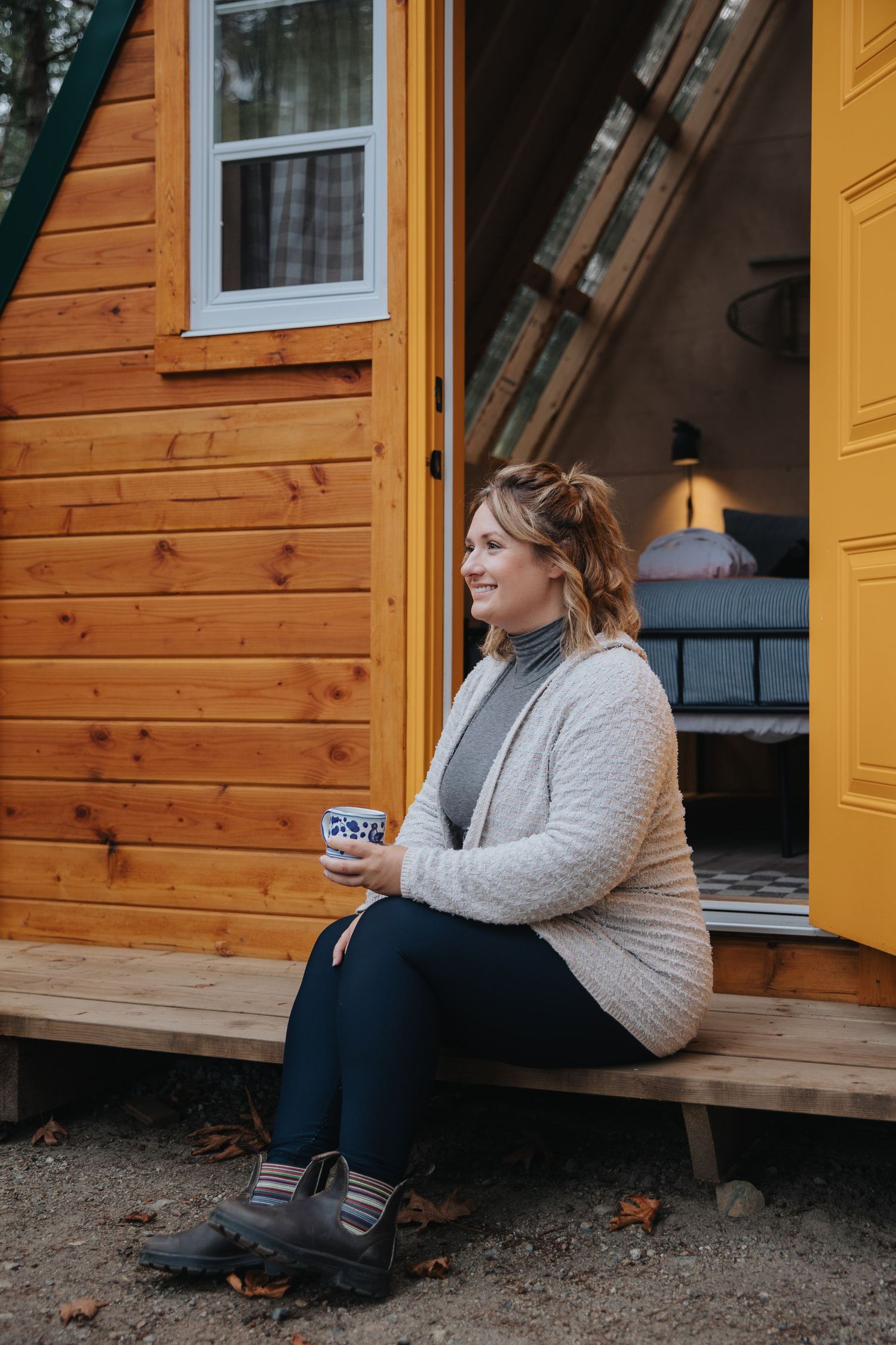 Person sitting on wooden cabin porch during autumn season.