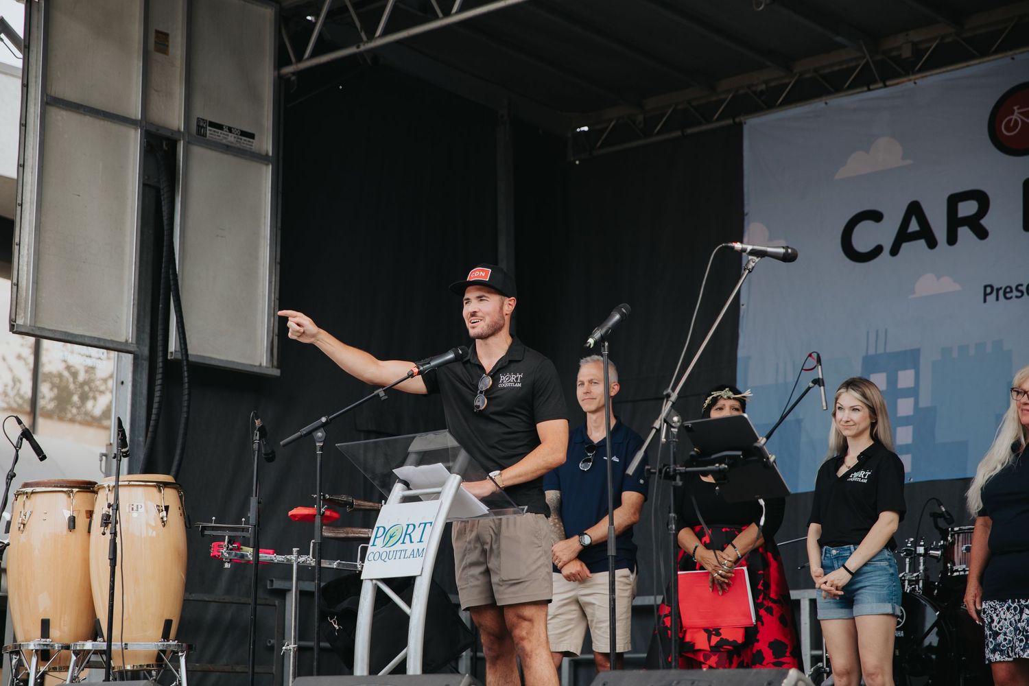 Wide shot of performers on stage during a daytime outdoor music festival.