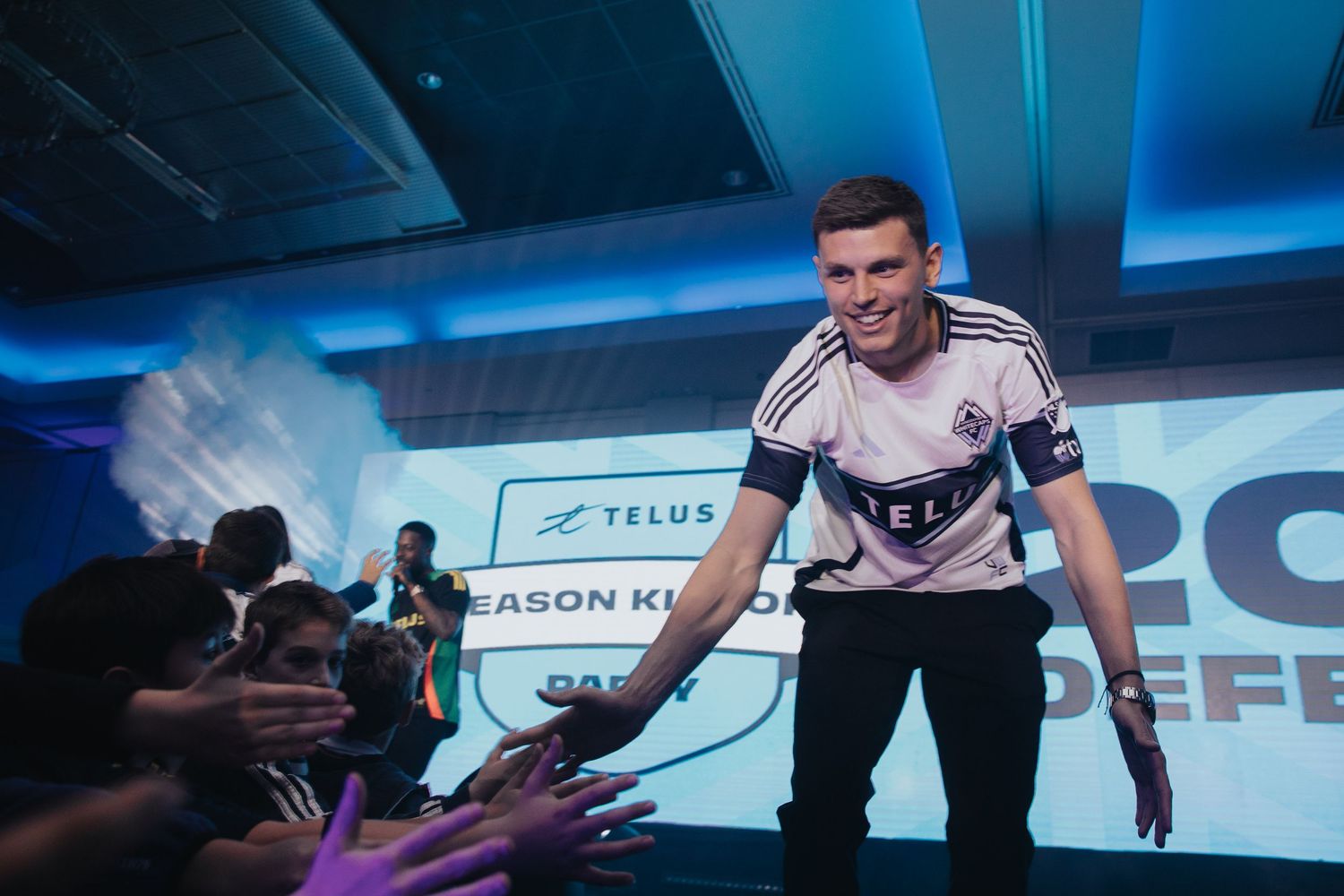 Professional esports players celebrating on stage with dramatic blue lighting at a gaming event.