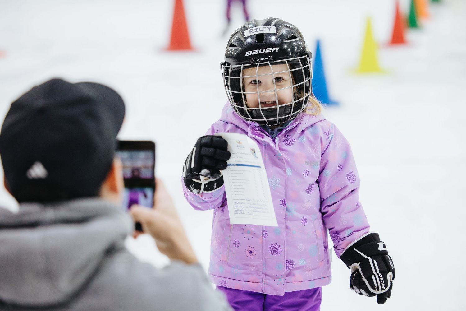 Young hockey players practice skating drills with colorful cones on an ice rink.