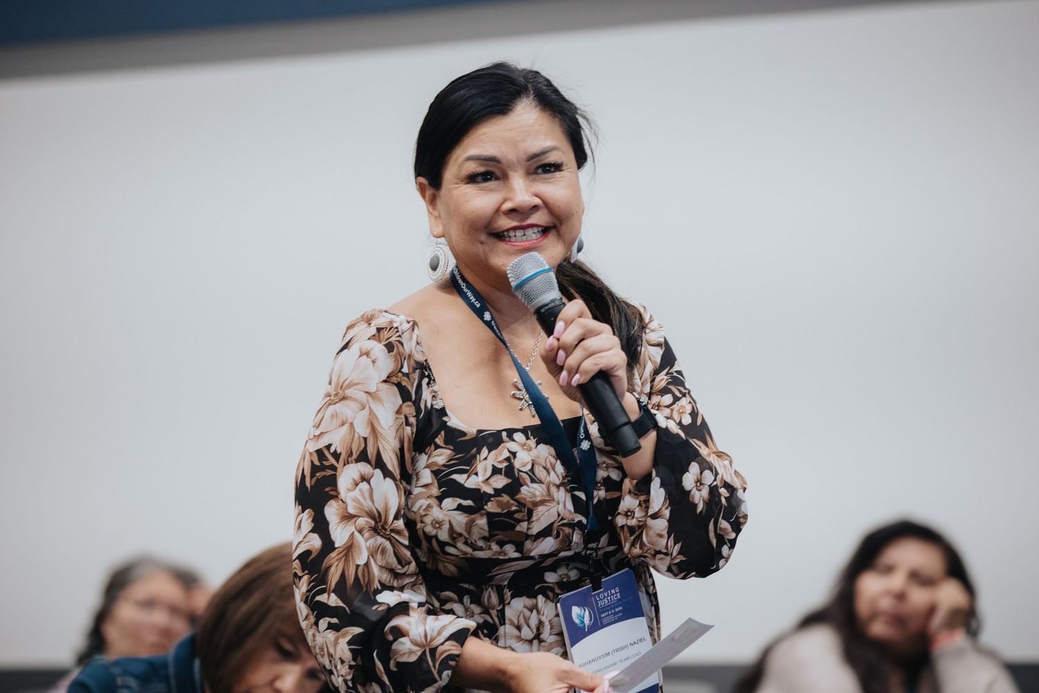 Speaker presenting at professional conference in bright meeting room.