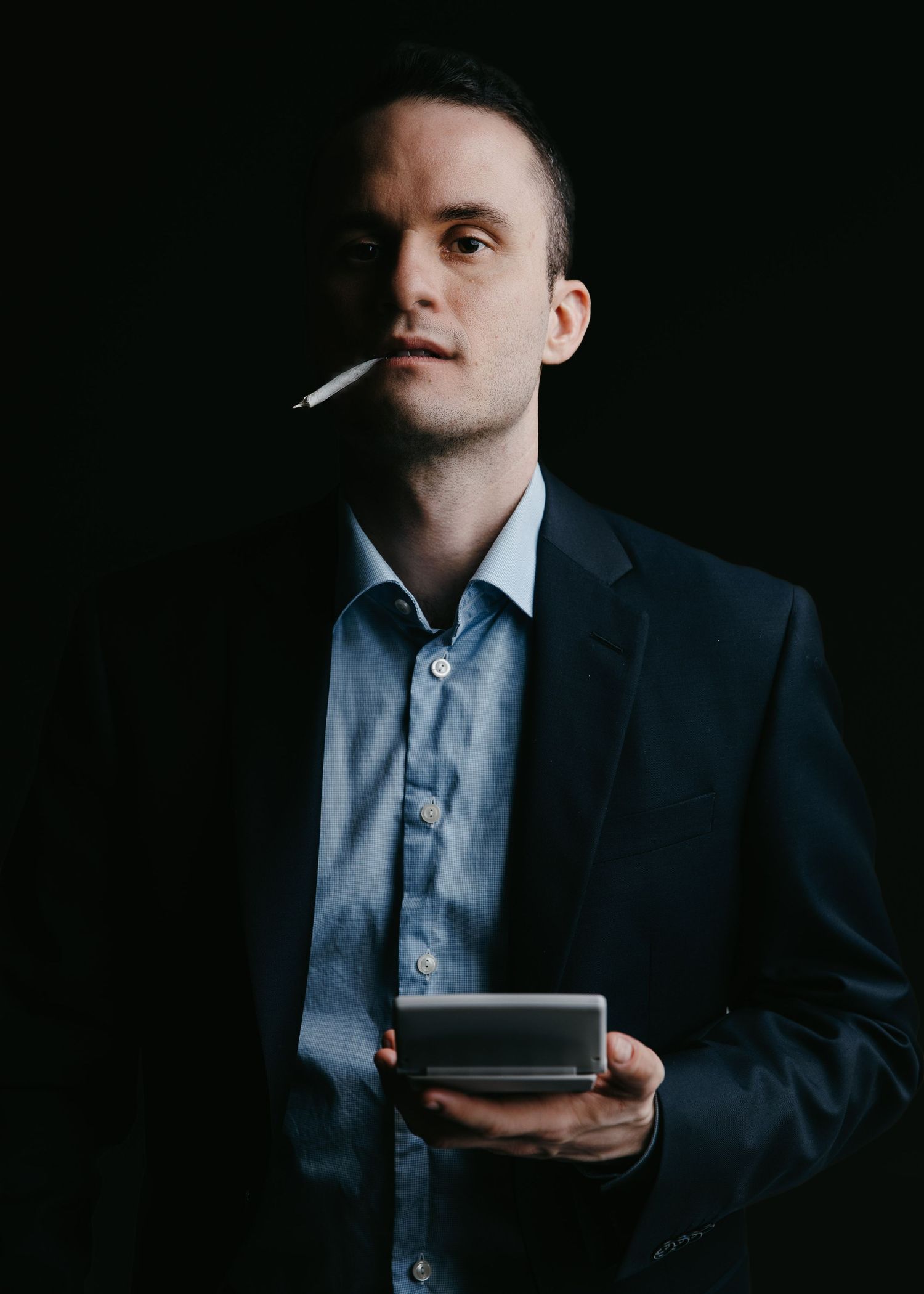 Dramatic low-key portraits of person in business attire holding electronic device.