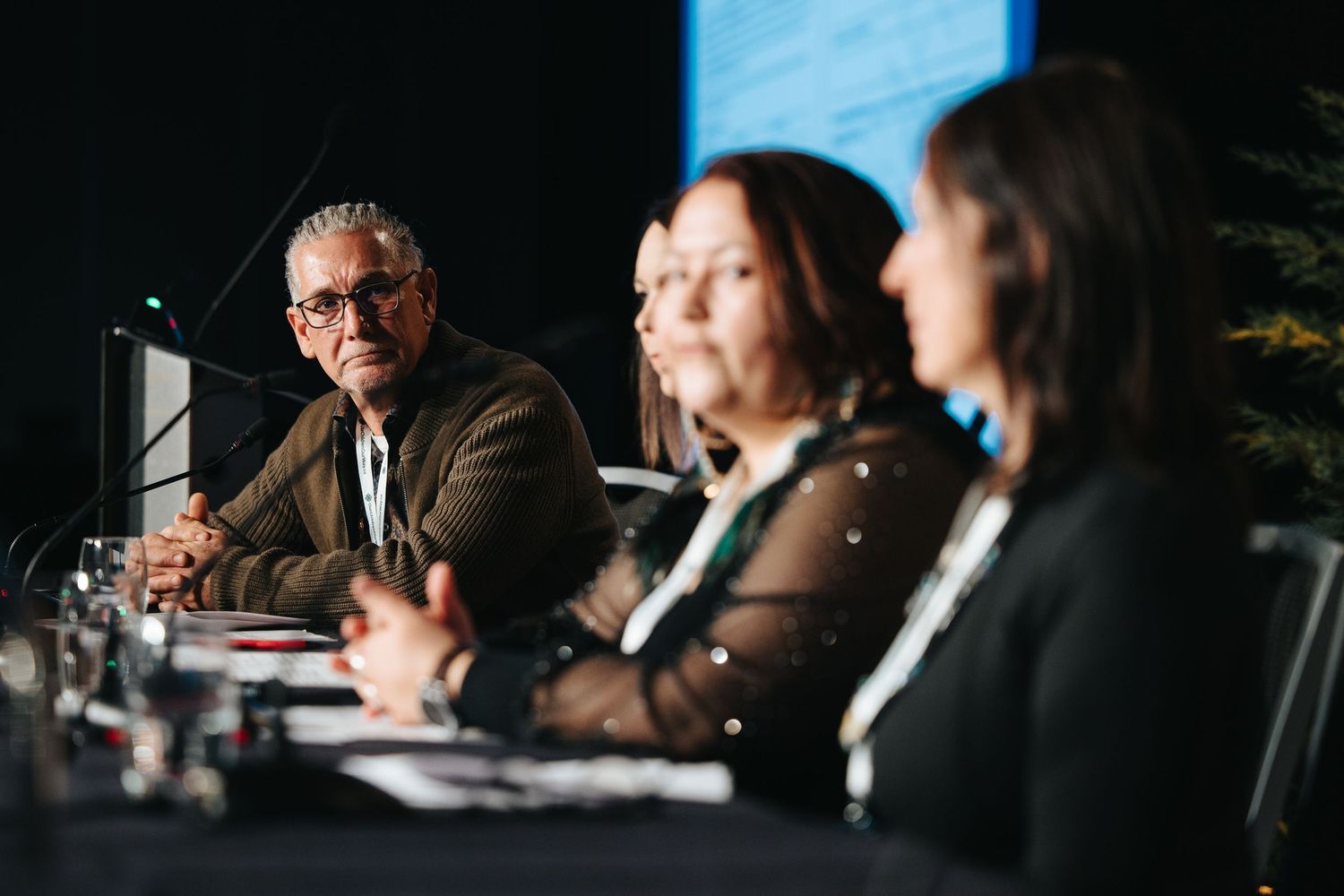 Panel of speakers sit at a conference table during a professional event discussion.