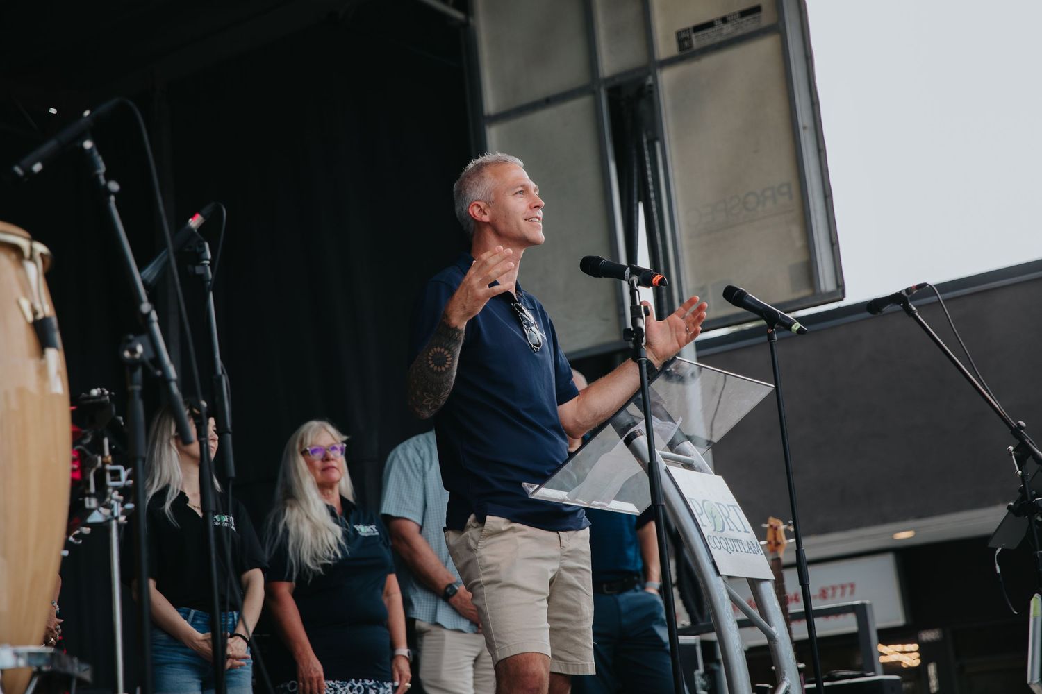 Musicians perform on stage at an outdoor concert venue with lighting and sound equipment.