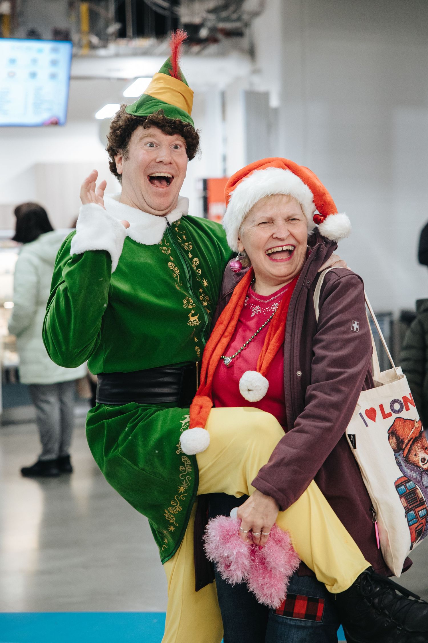 Two people in festive holiday costumes, one dressed as an elf in green, sharing a joyful moment.