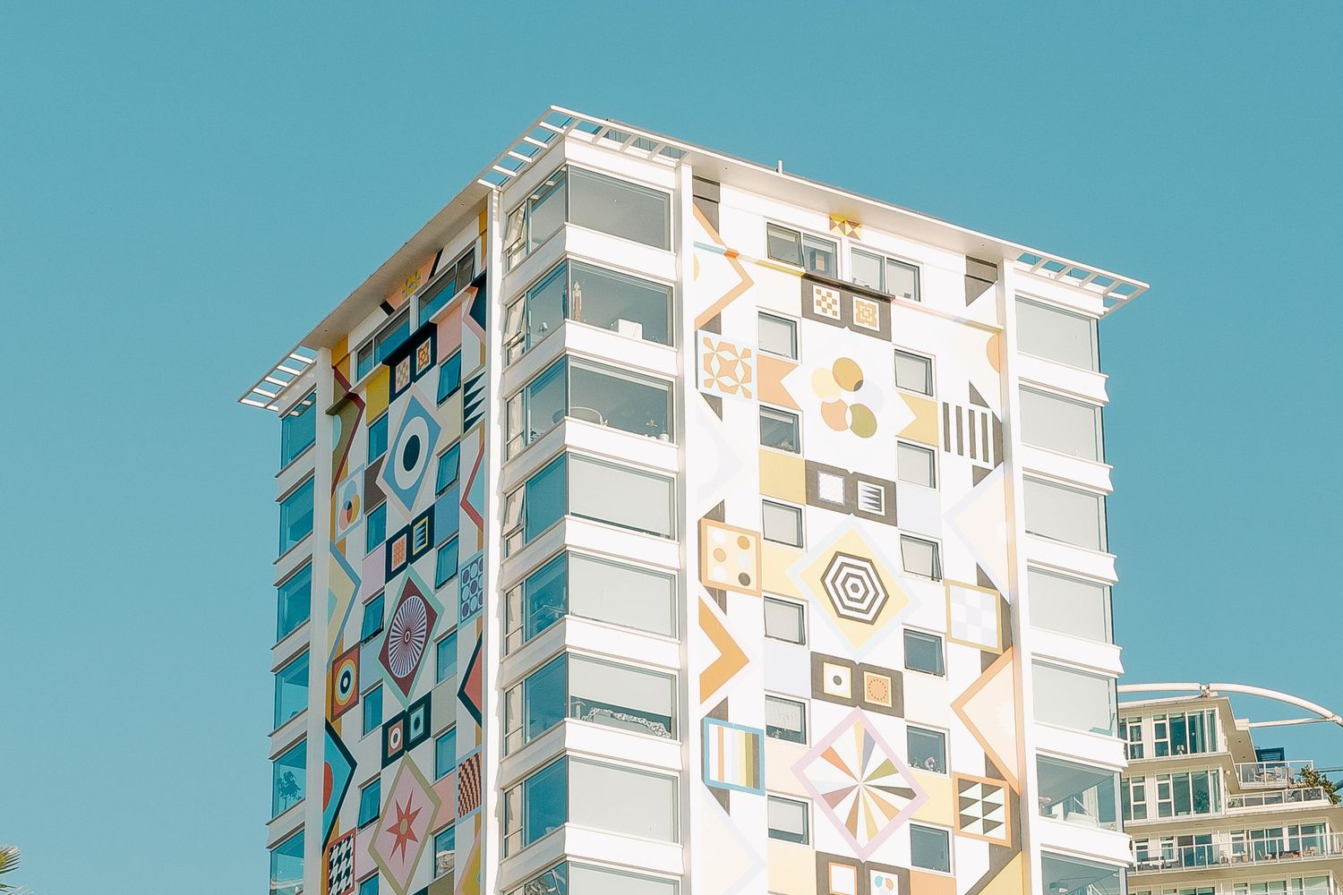 Modern high-rise building with colorful geometric art mural on exterior wall.