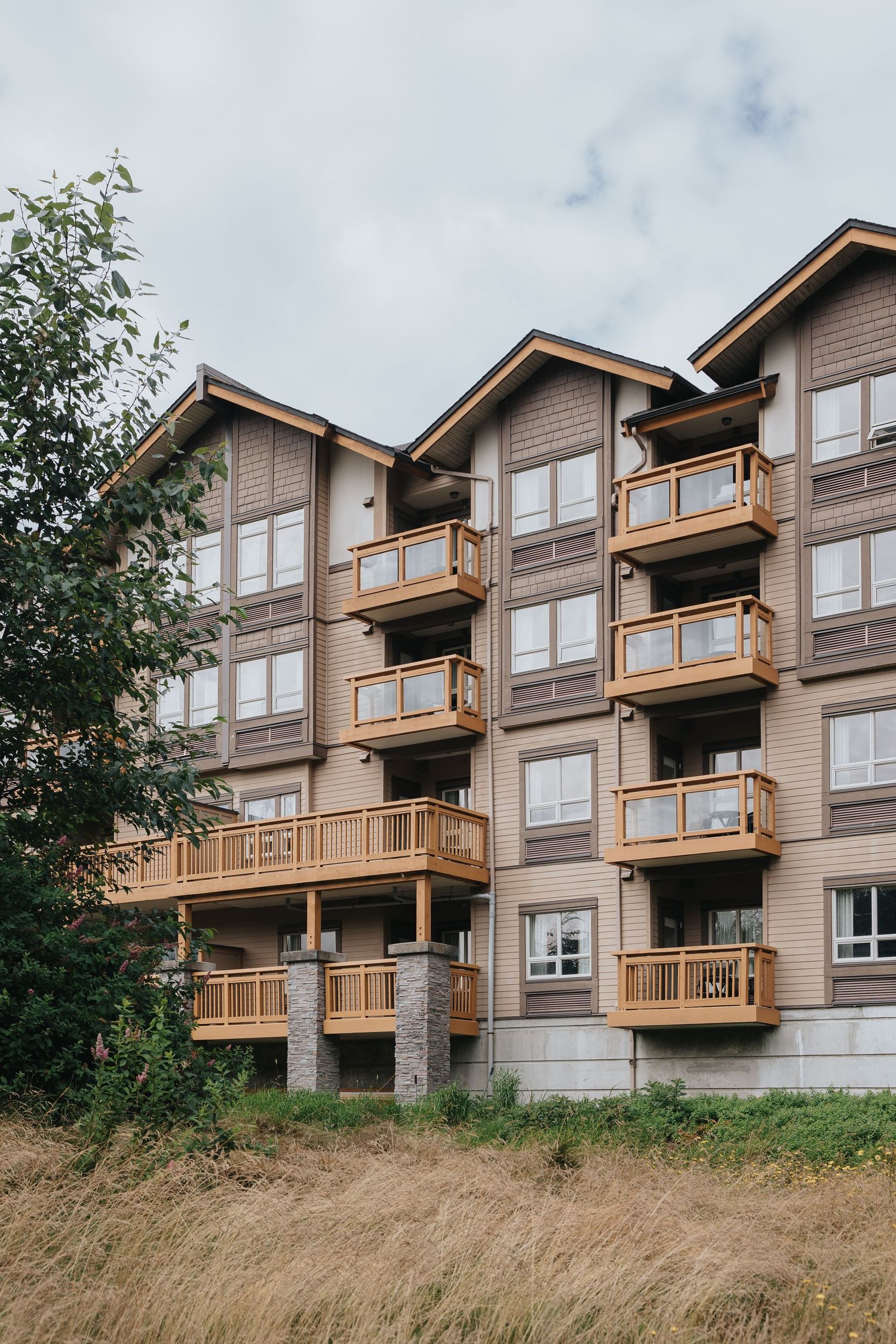 Modern apartment complex with wooden balconies and large windows on hillside.