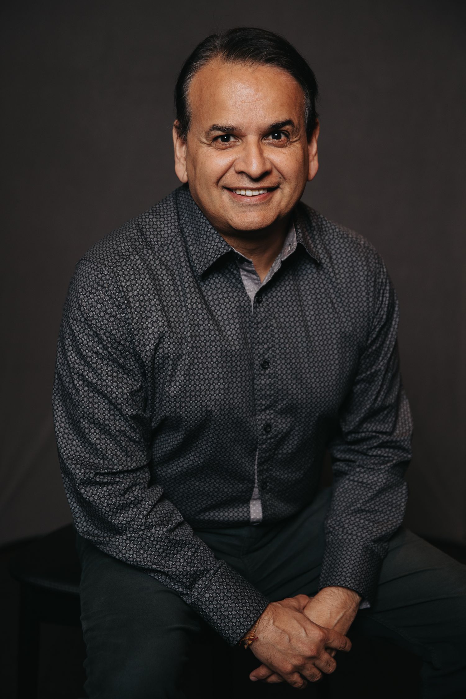 Portrait series showing warm expressions in dotted dark shirt against black background.