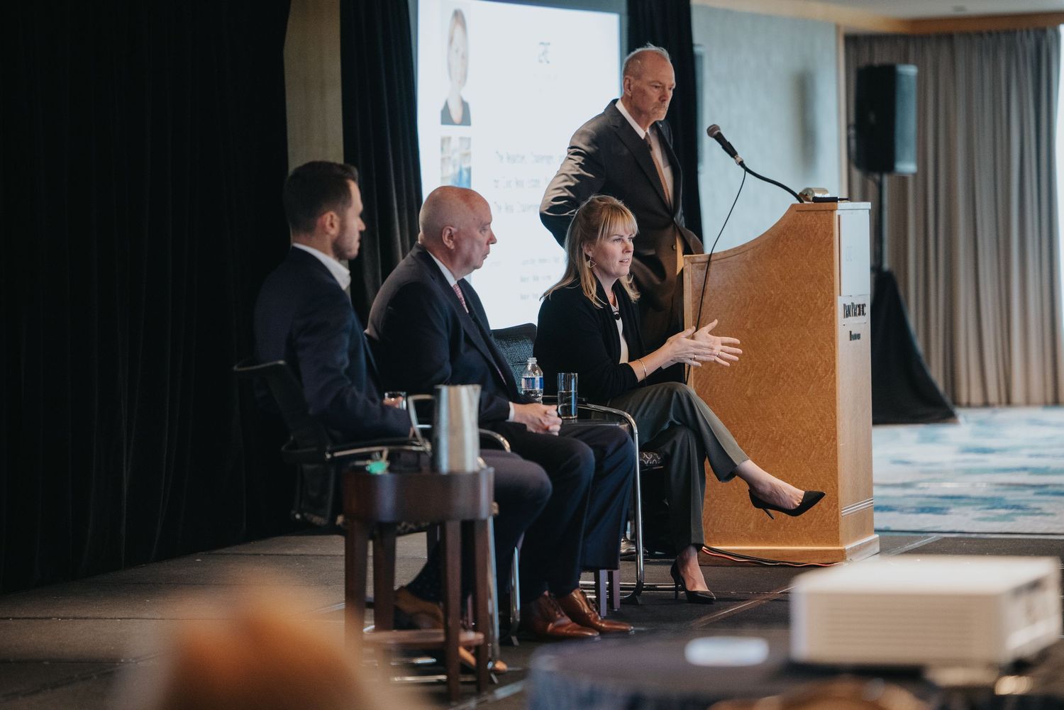 Panel discussion at a business conference with speakers at podium and seated guests.
