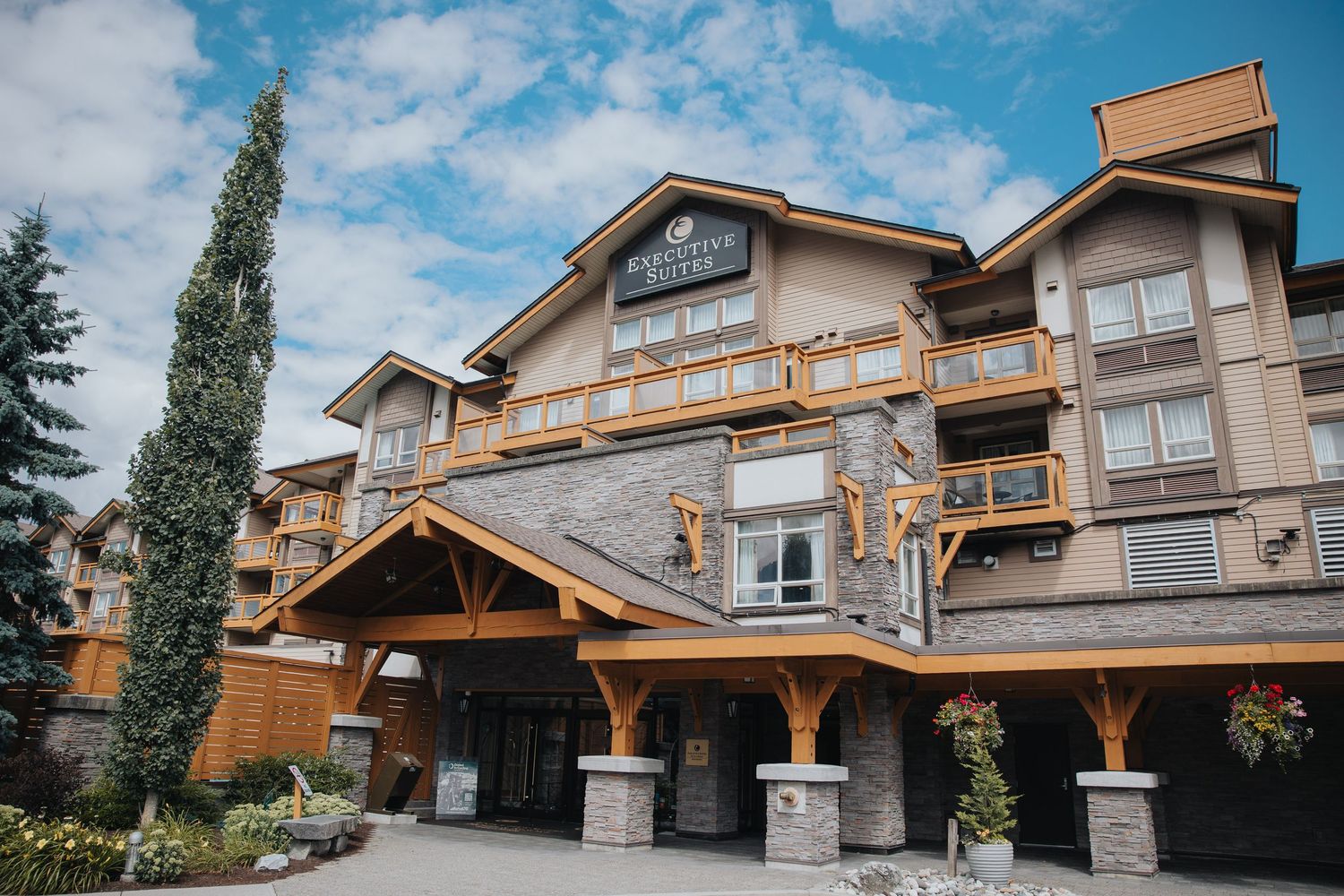 Upscale apartment complex featuring mountain lodge architecture with stone pillars and wooden trim.