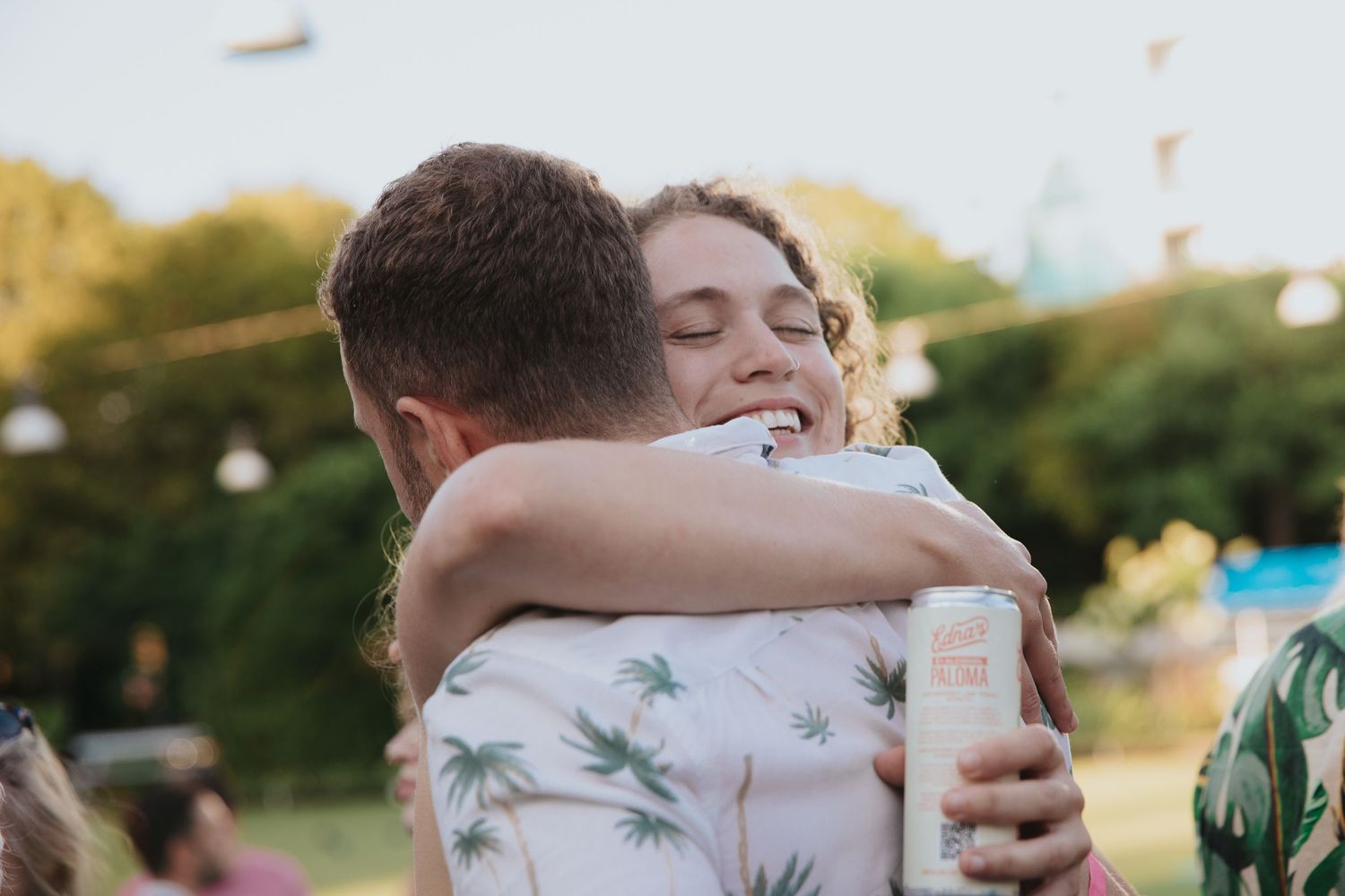 A couple in floral attire embraces during an outdoor sunset photoshoot in a natural setting.
