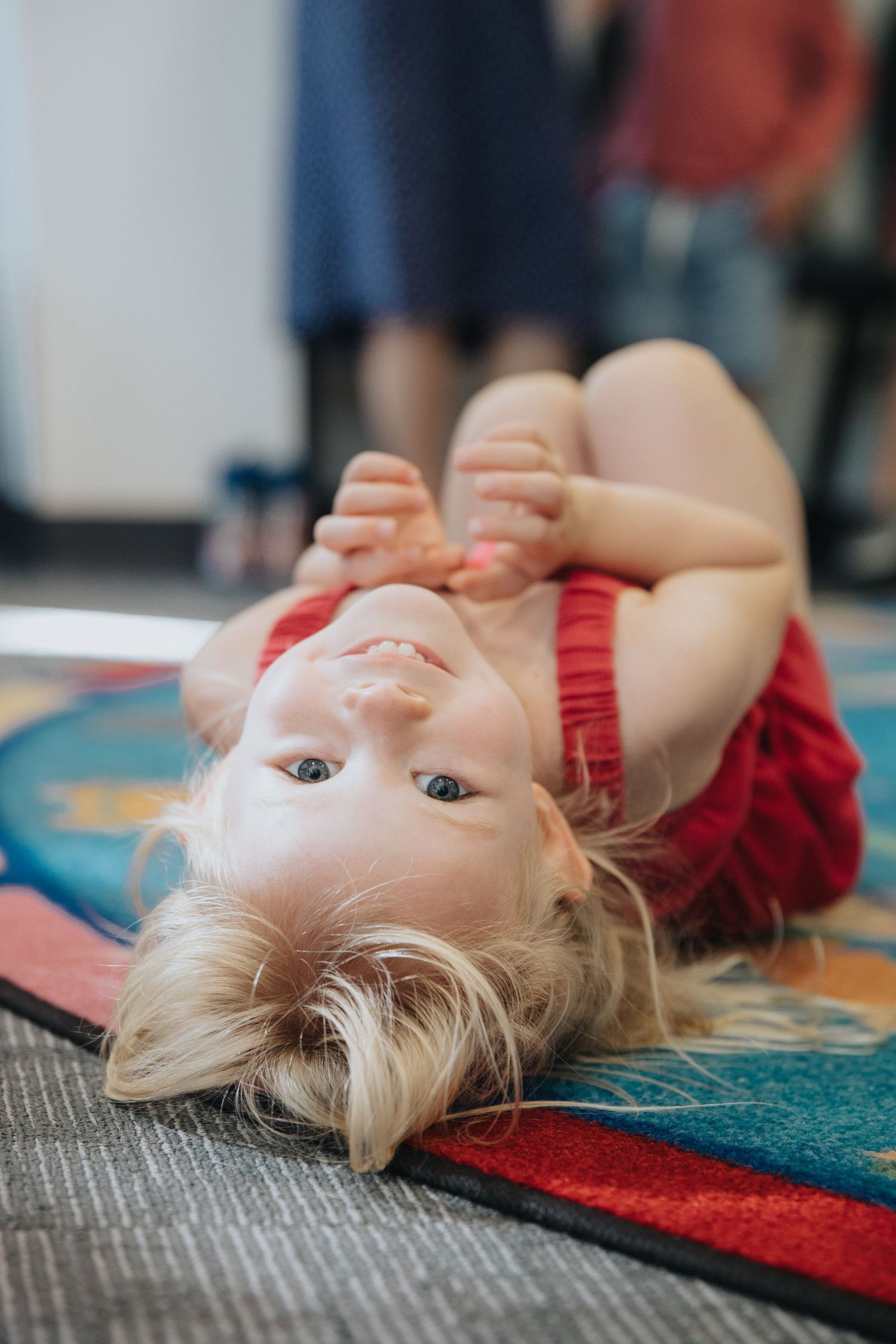 A discarded doll with blonde hair lies on a colorful carpet.