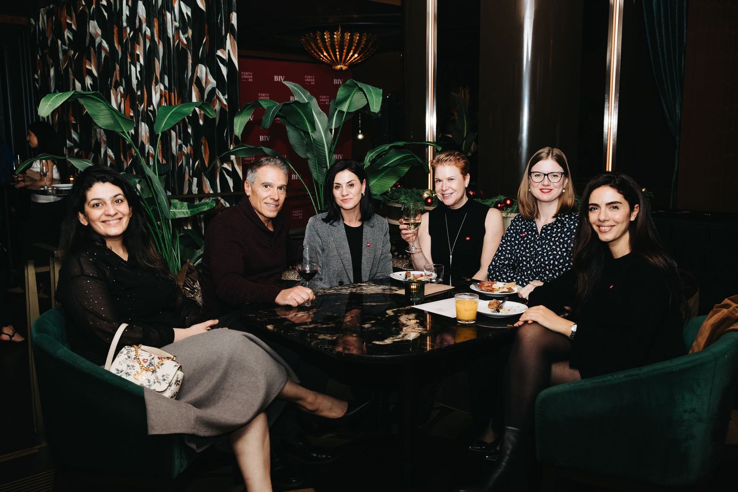 Group of people seated around a dark table in an elegant restaurant setting.