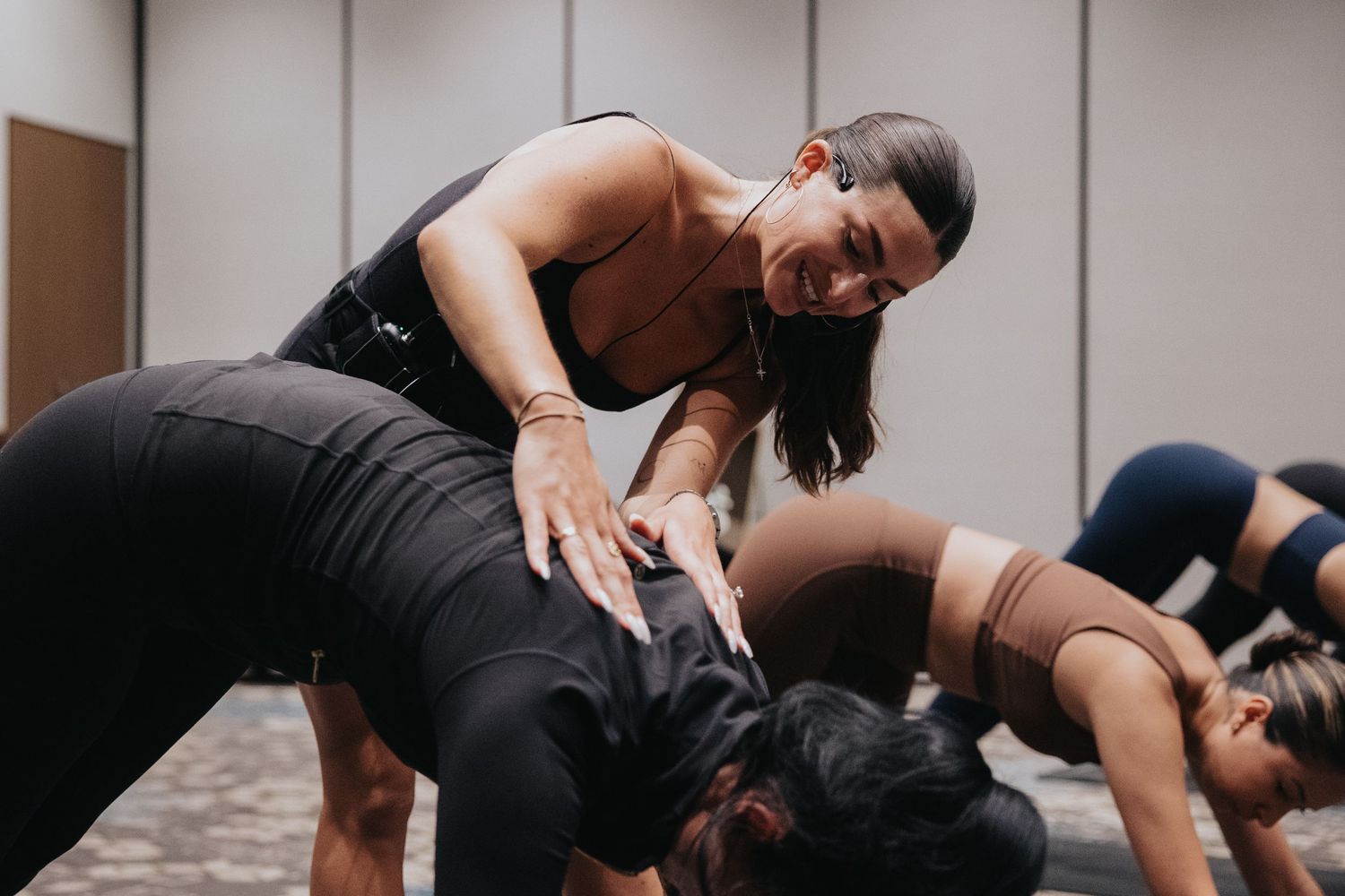 Group fitness class participants stretching on exercise mats in a studio setting.