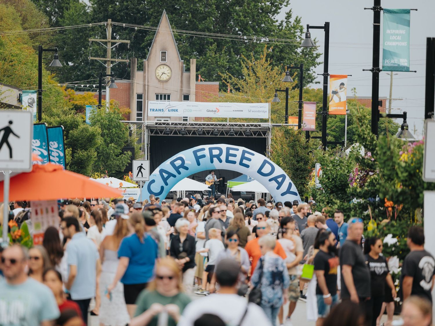 Aerial view of a bustling street festival with crowds and vendor tents.