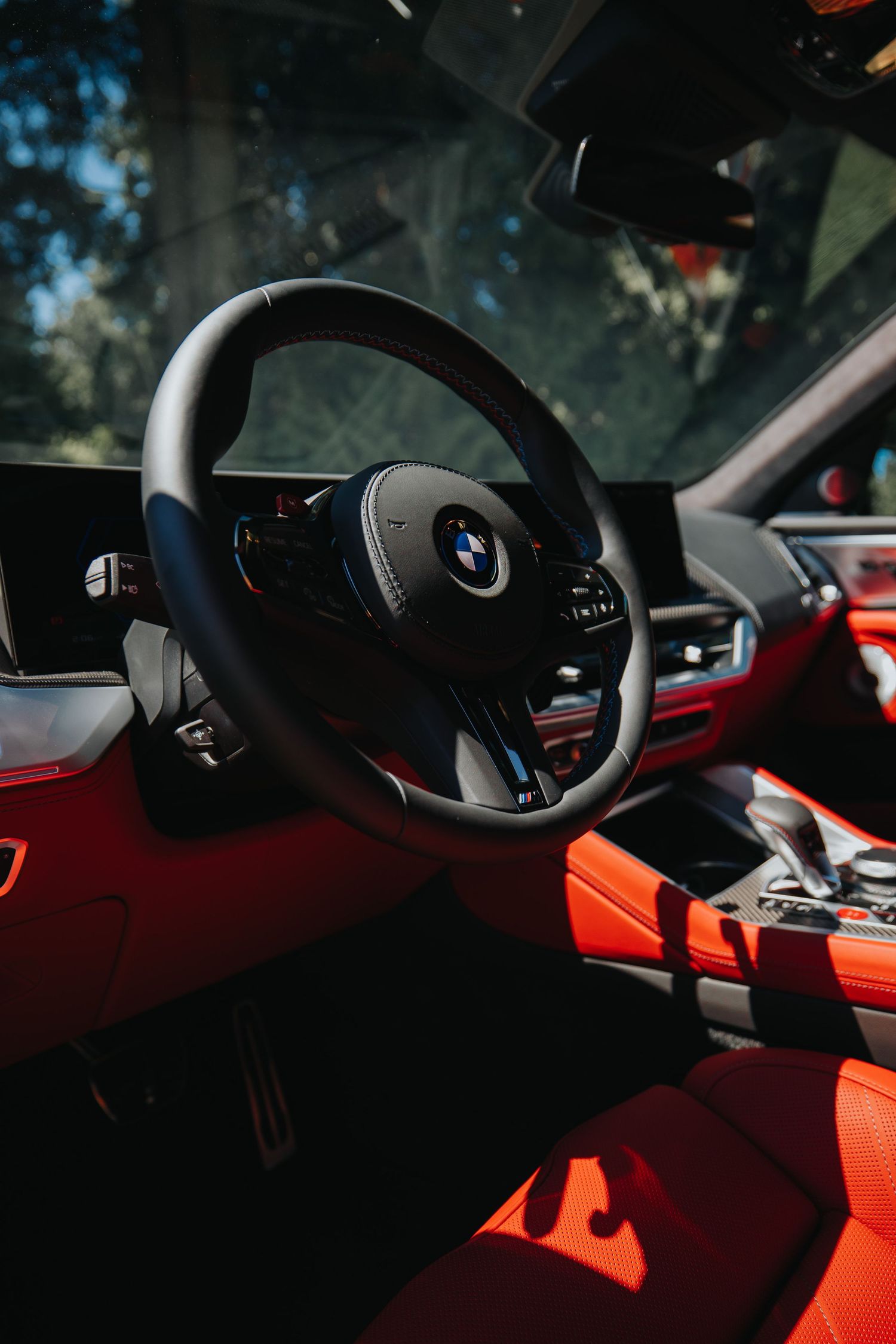 Interior view of a luxury BMW vehicle dashboard with red leather upholstery.