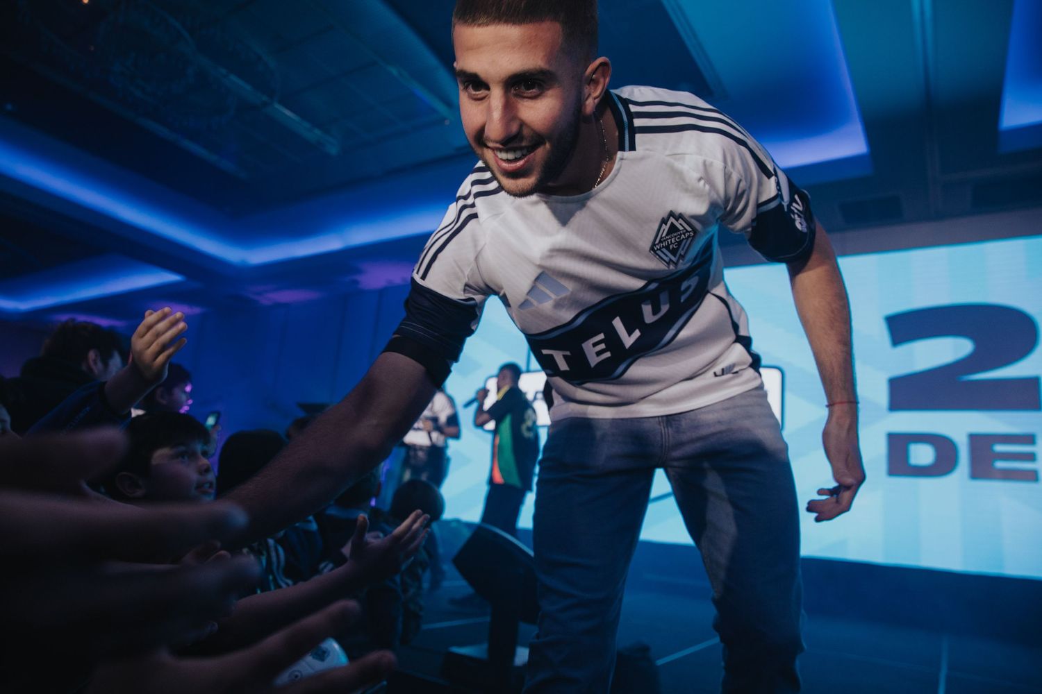 Esports players in white Telus jerseys interacting with fans at a gaming event.