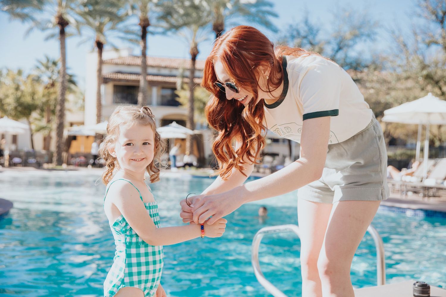 Playful swimming pool interactions at a palm-tree lined resort.