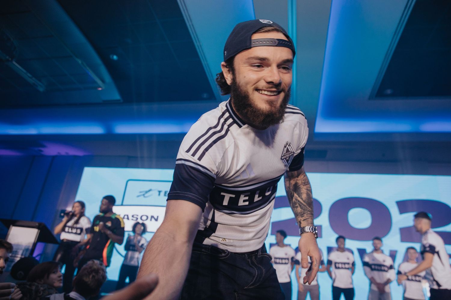Esports players in white jerseys engaging with audience at a competitive gaming event.