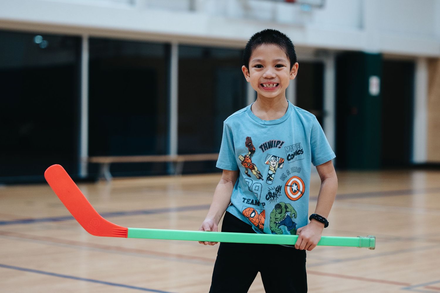Children practicing hockey skills with colorful sticks in an indoor facility.