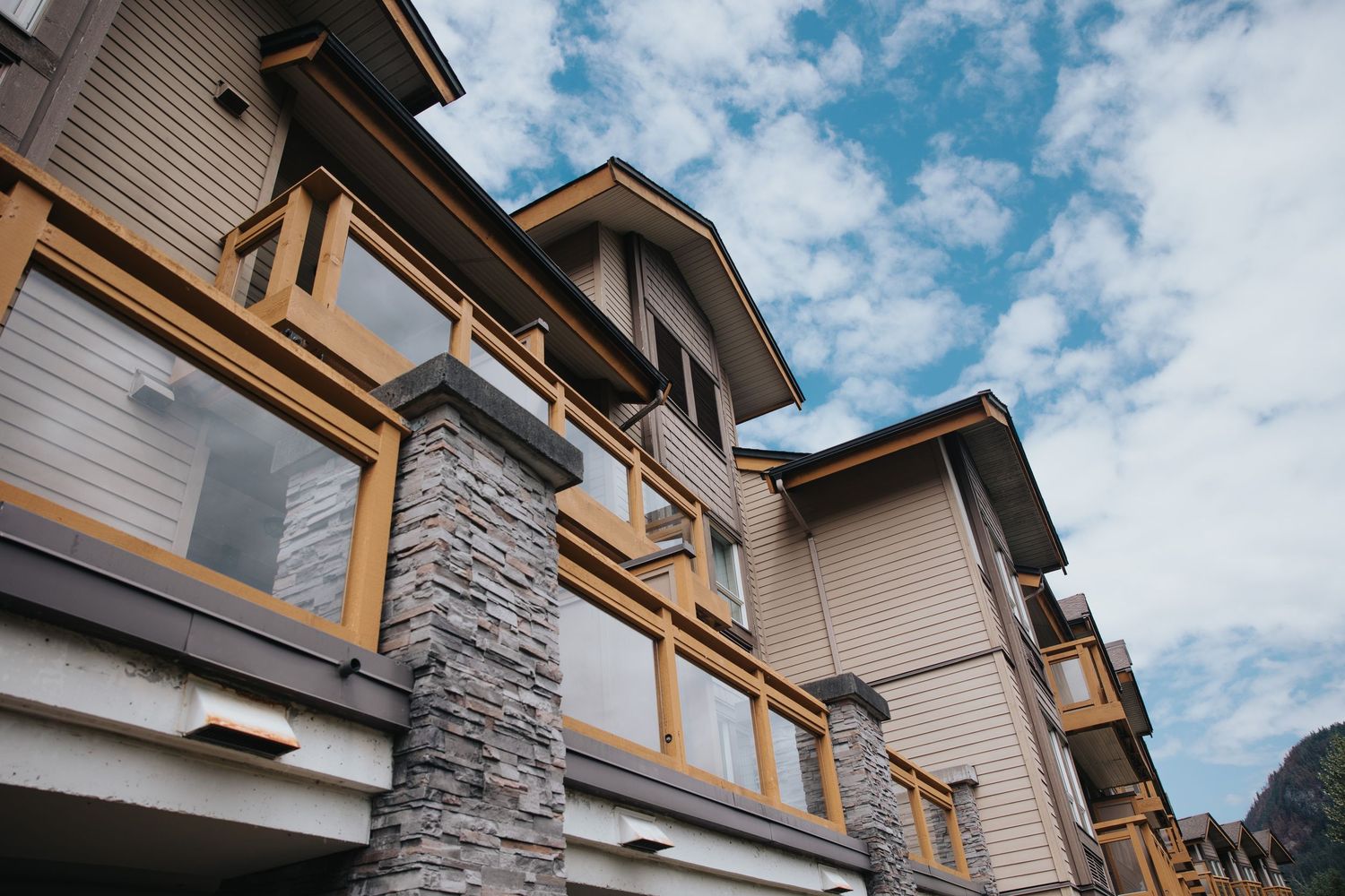 Contemporary lodge architecture featuring stone pillars and wooden trim against blue sky.