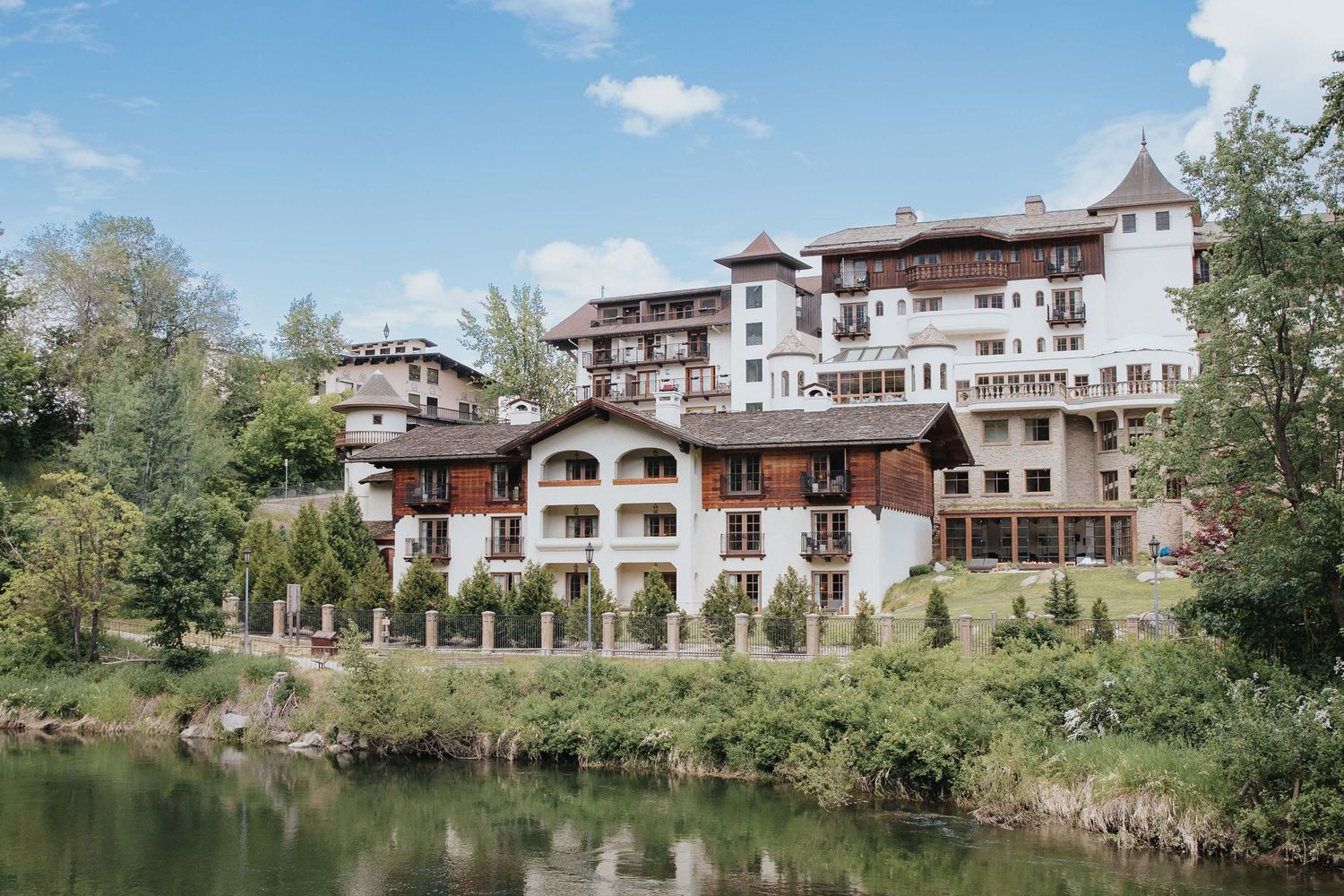Panoramic view of a luxury resort hotel with traditional architecture nestled along a peaceful lake.