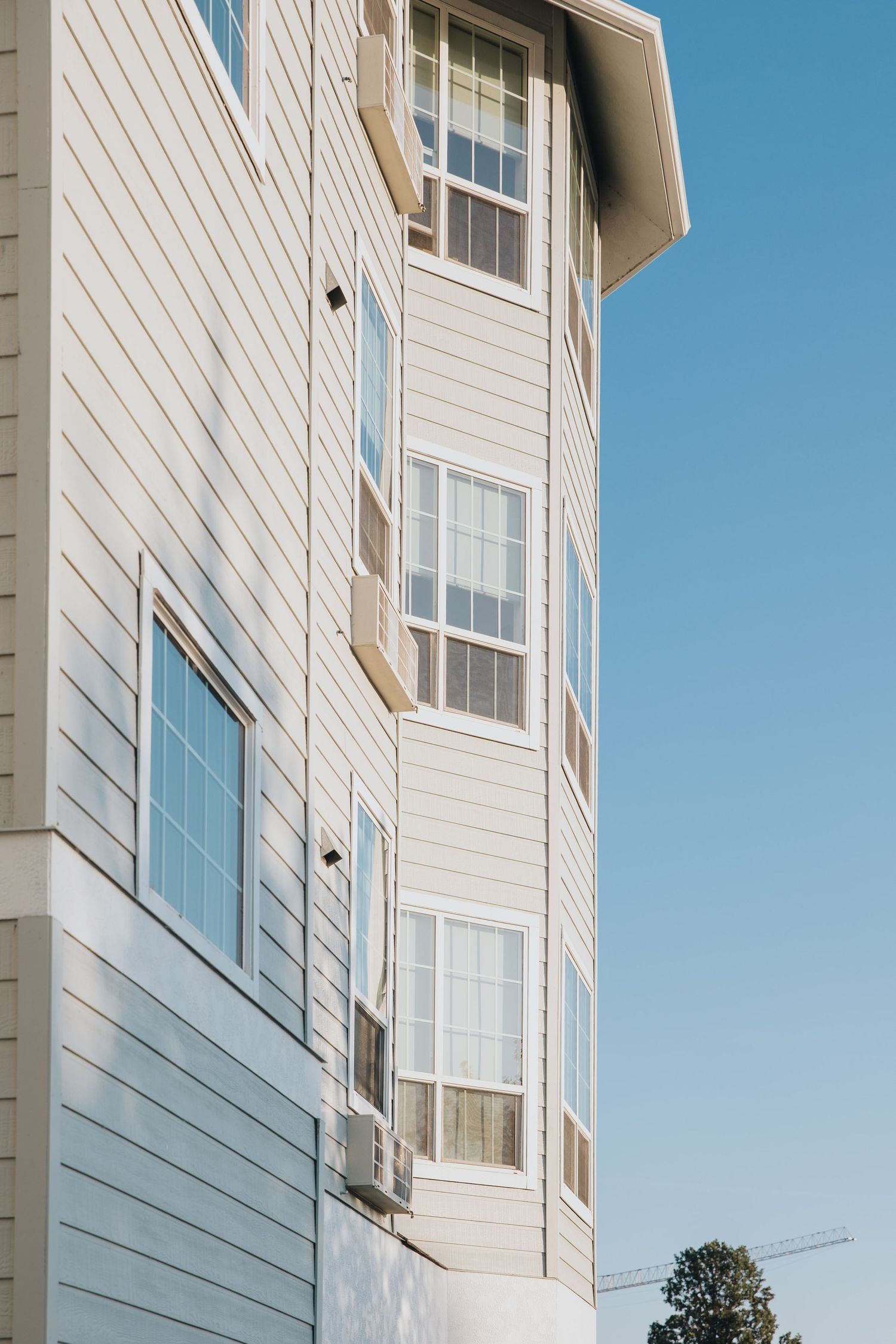 White apartment building exterior with large windows against bright blue sky.