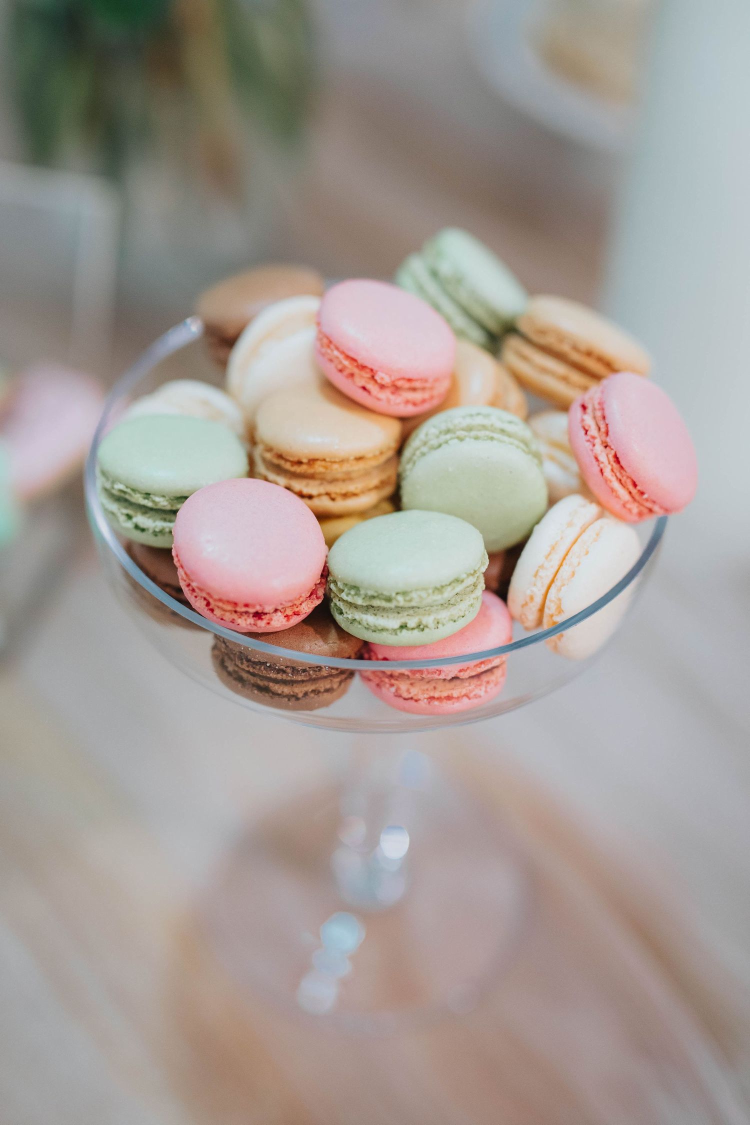 Colorful French macarons in pastel pink, green and white arranged on a glass cake stand.