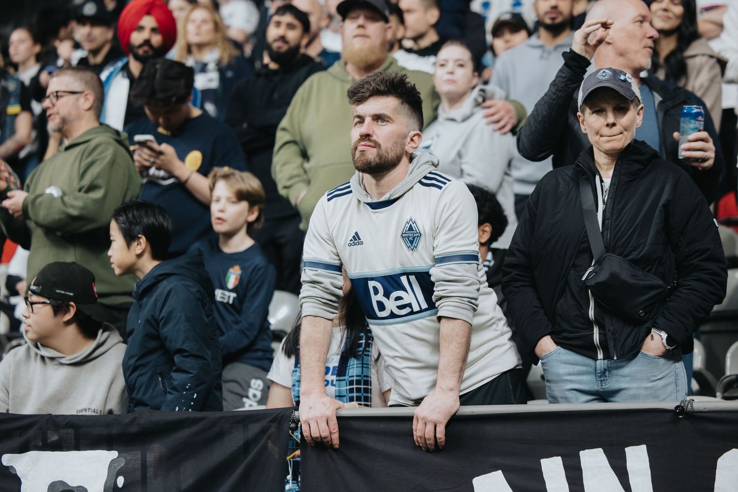 Soccer fans in the stands cheer and watch intently during an exciting match at the stadium.