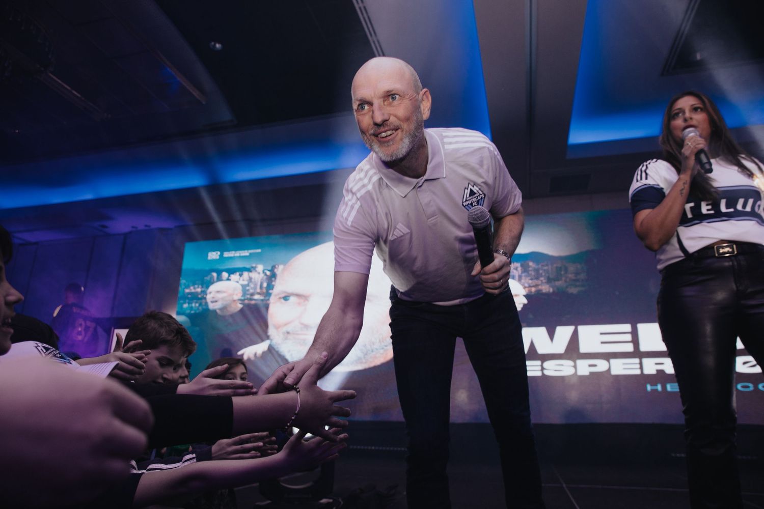 Event staff and presenters interacting on stage during gaming conference presentation.