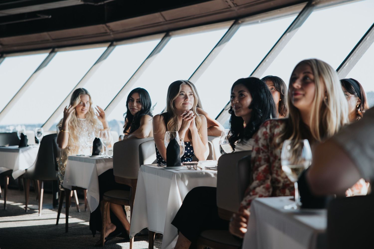 People gathered in a modern venue with slanted windows and natural lighting.